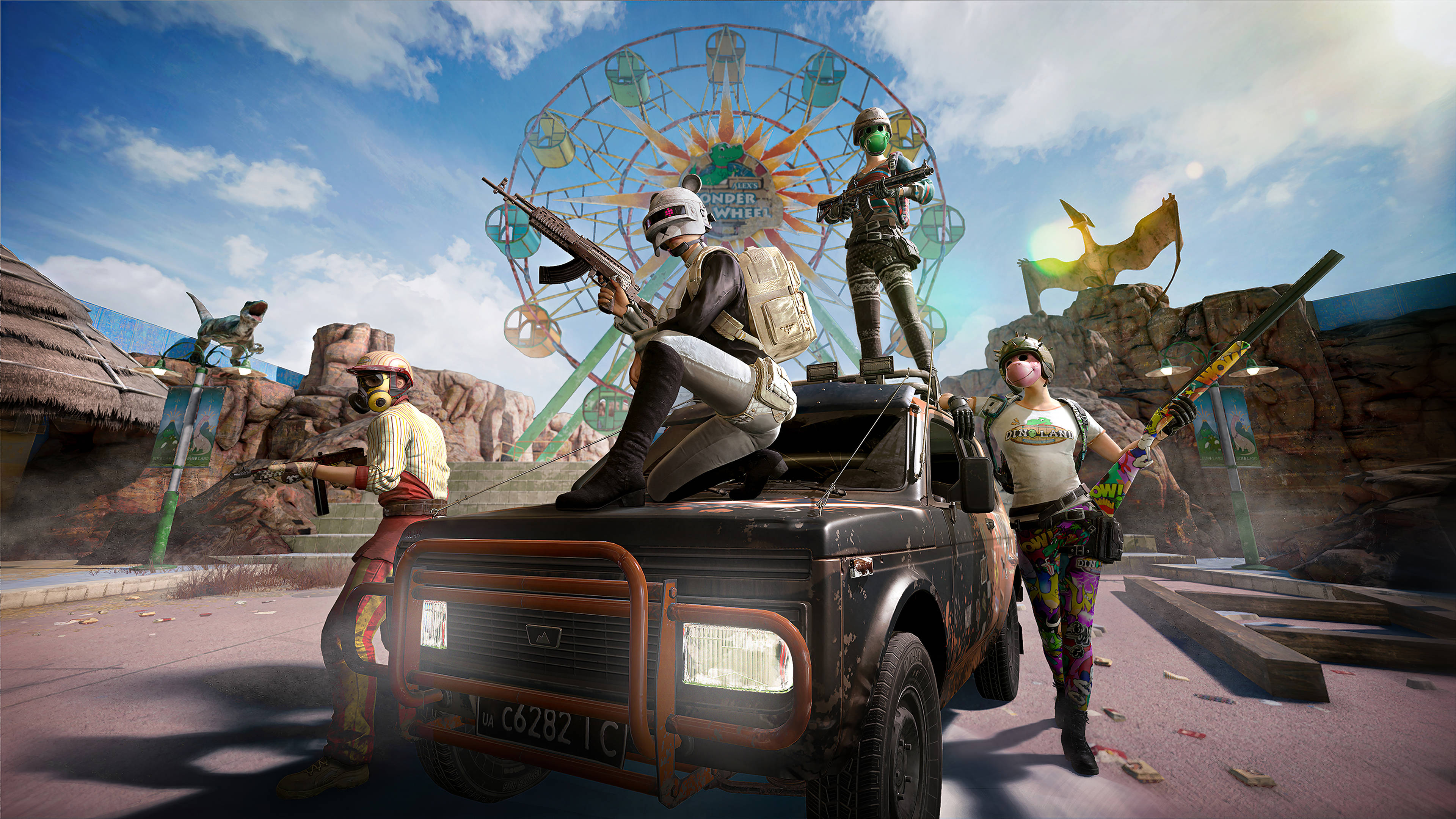 PUBG 桌布 壁紙 — 三名身穿彩色裝備的武裝玩家站在沙漠遊樂園中一輛堅固卡車的頂部和旁邊，園內有巨大的摩天輪和恐龍。