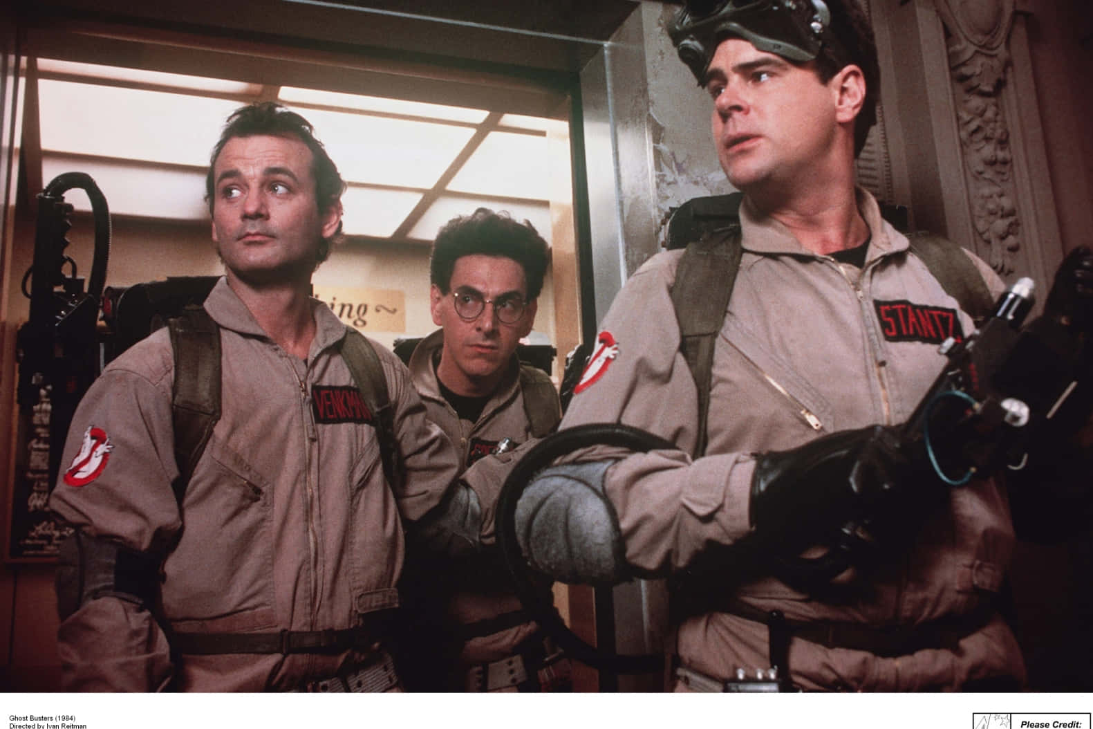 Ghostbusters 桌布 壁紙 — 三名身穿米色制服、背著質子背包的捉鬼敢死隊在華麗的走廊中警覺地站立，專注地向上看。