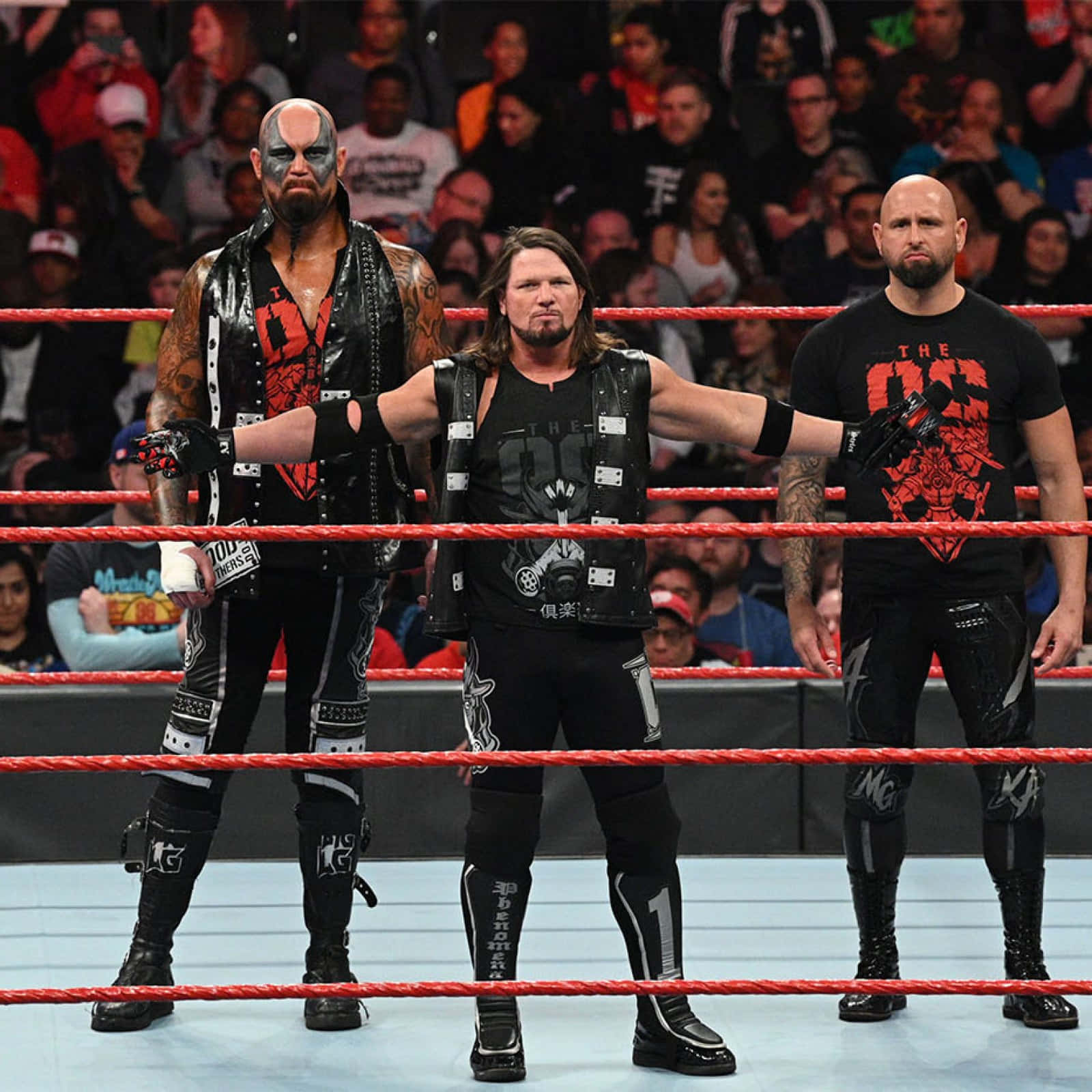 三名職業摔角手在摔角擂台上擺姿勢，背景有粉絲。 — WWE GIF 壁紙