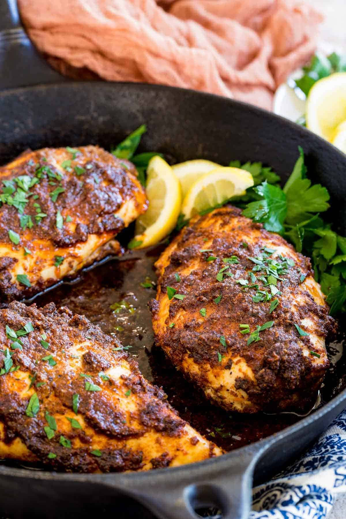 Blackened Chicken 桌布 壁紙 — 三塊金黃色的雞胸肉塗上濃郁的深色醬汁和新鮮歐芹，放在鑄鐵煎鍋中，配上檸檬角和蔬菜。