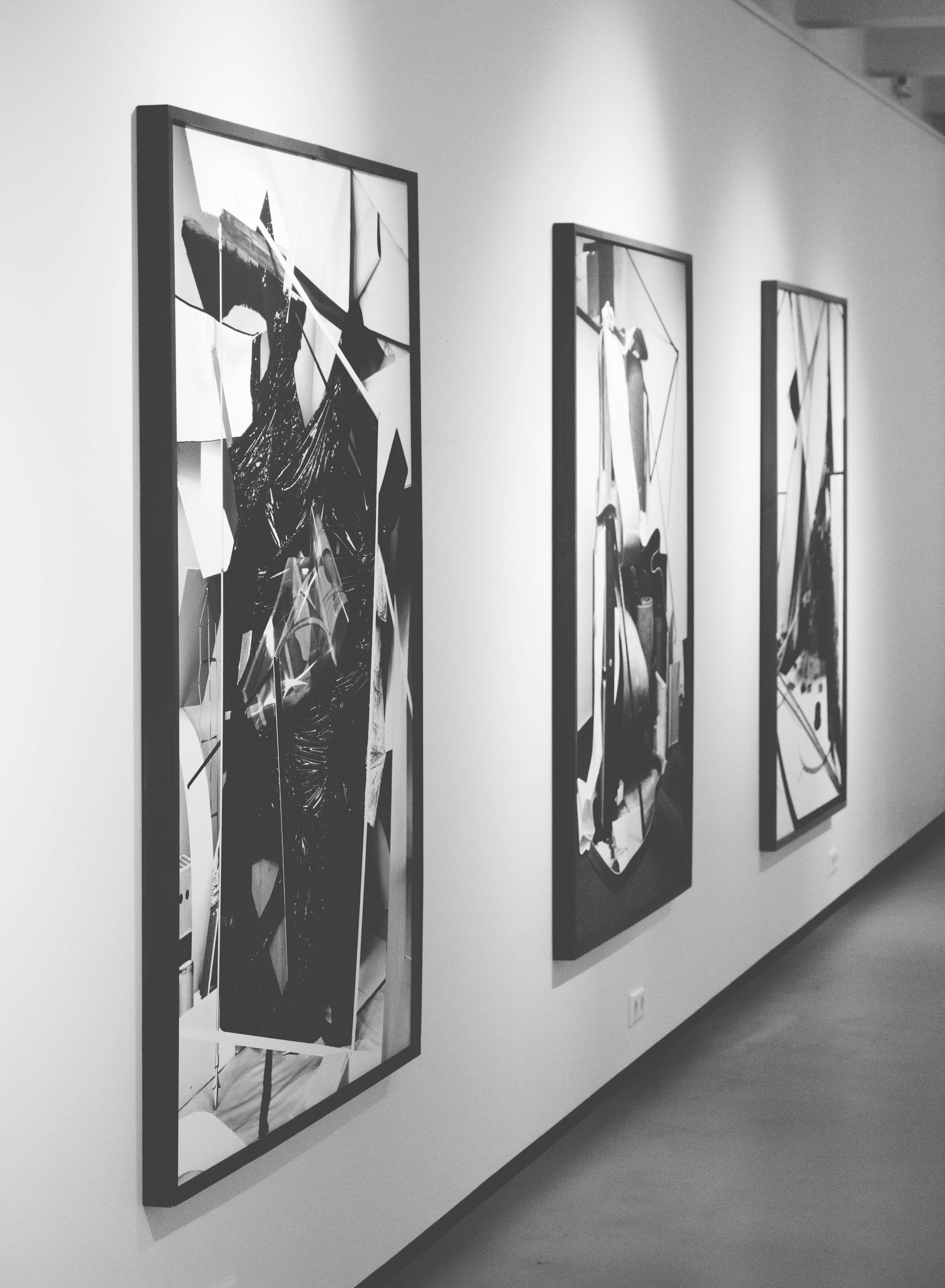 Gallery 桌布 壁紙 — 三幅大型黑白抽象藝術品掛在極簡主義畫廊走廊中，光線強烈。