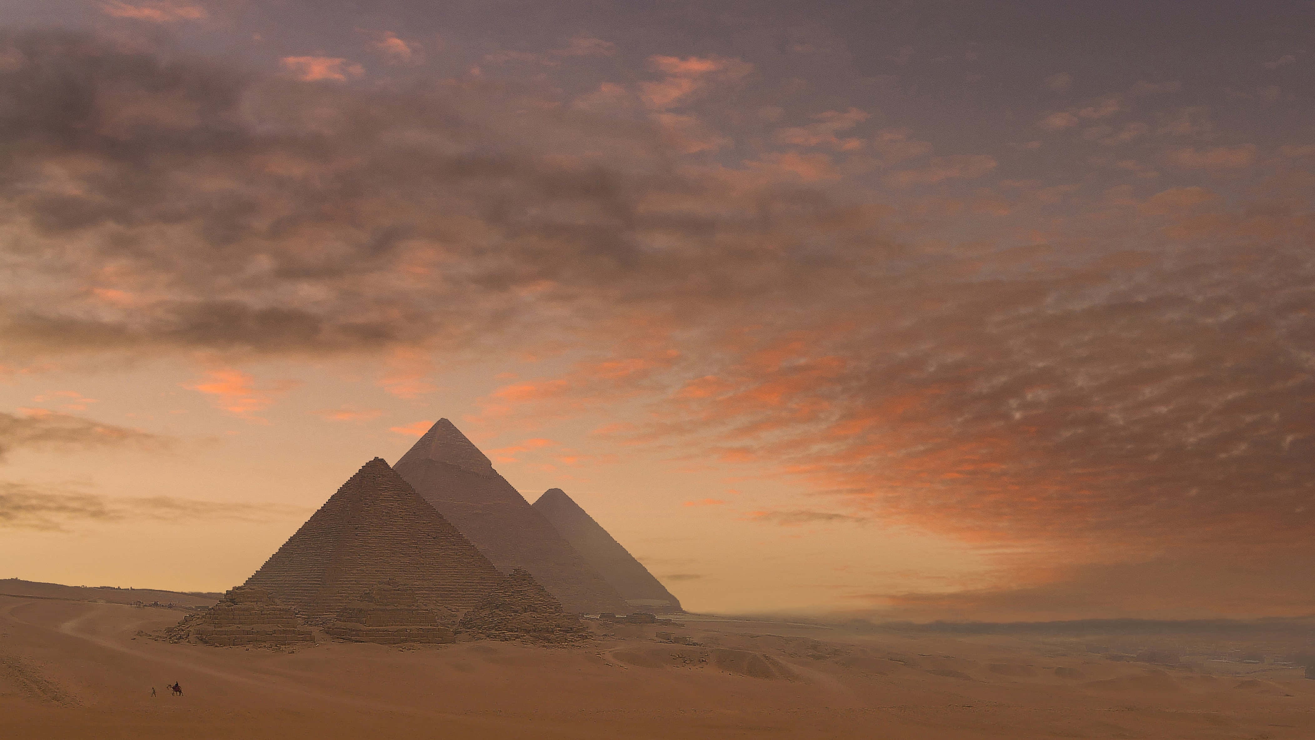 Ancient Egypt 桌布 壁紙 — 三座古老金字塔從金色沙漠中升起，天空佈滿橙色和紫色雲彩，呈現戲劇性的日落景象。