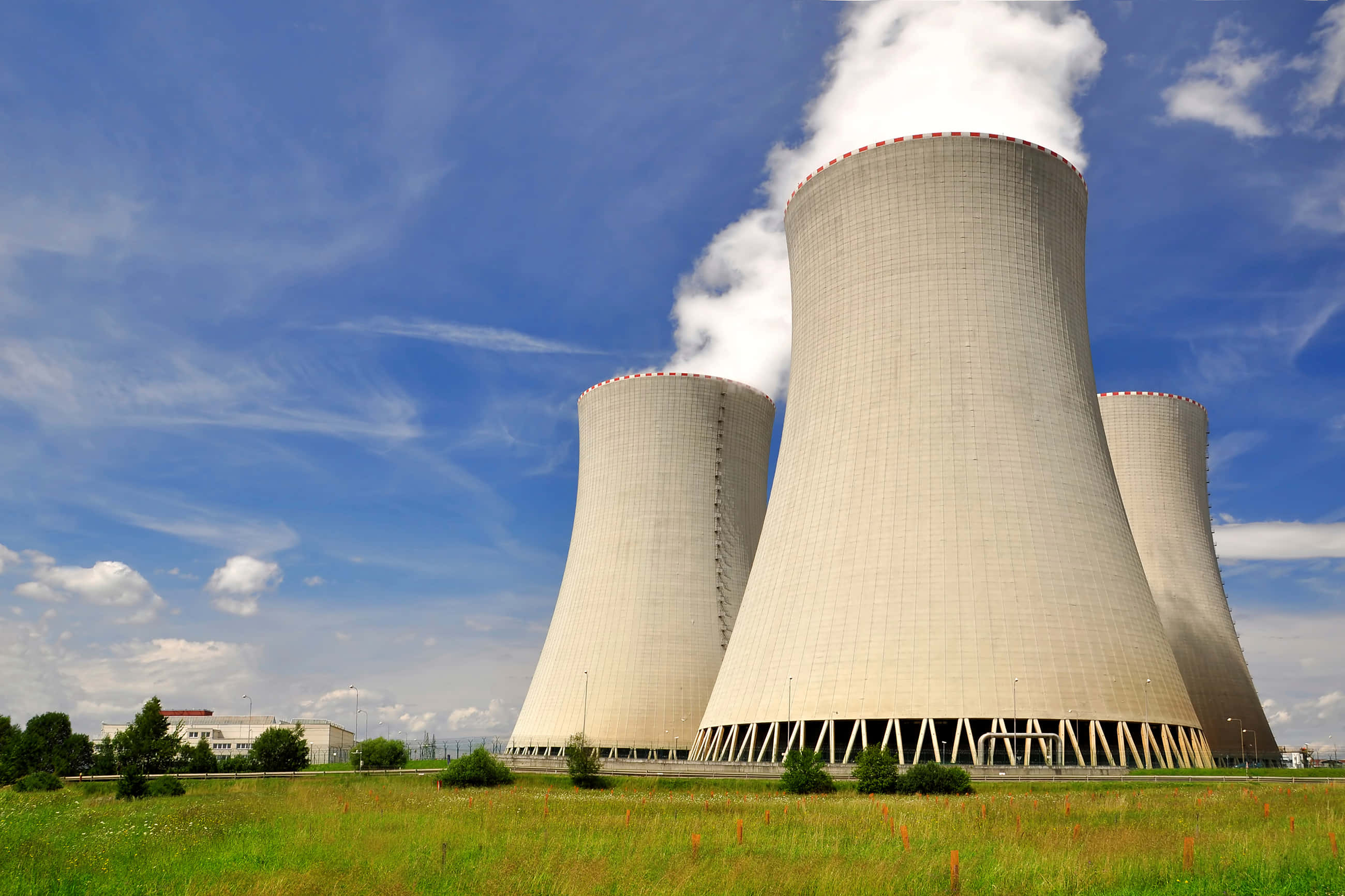 Energy 桌布 壁紙 — 三座巨大的核電廠冷卻塔在綠色田野上方，對著明亮的藍天排放蒸汽。