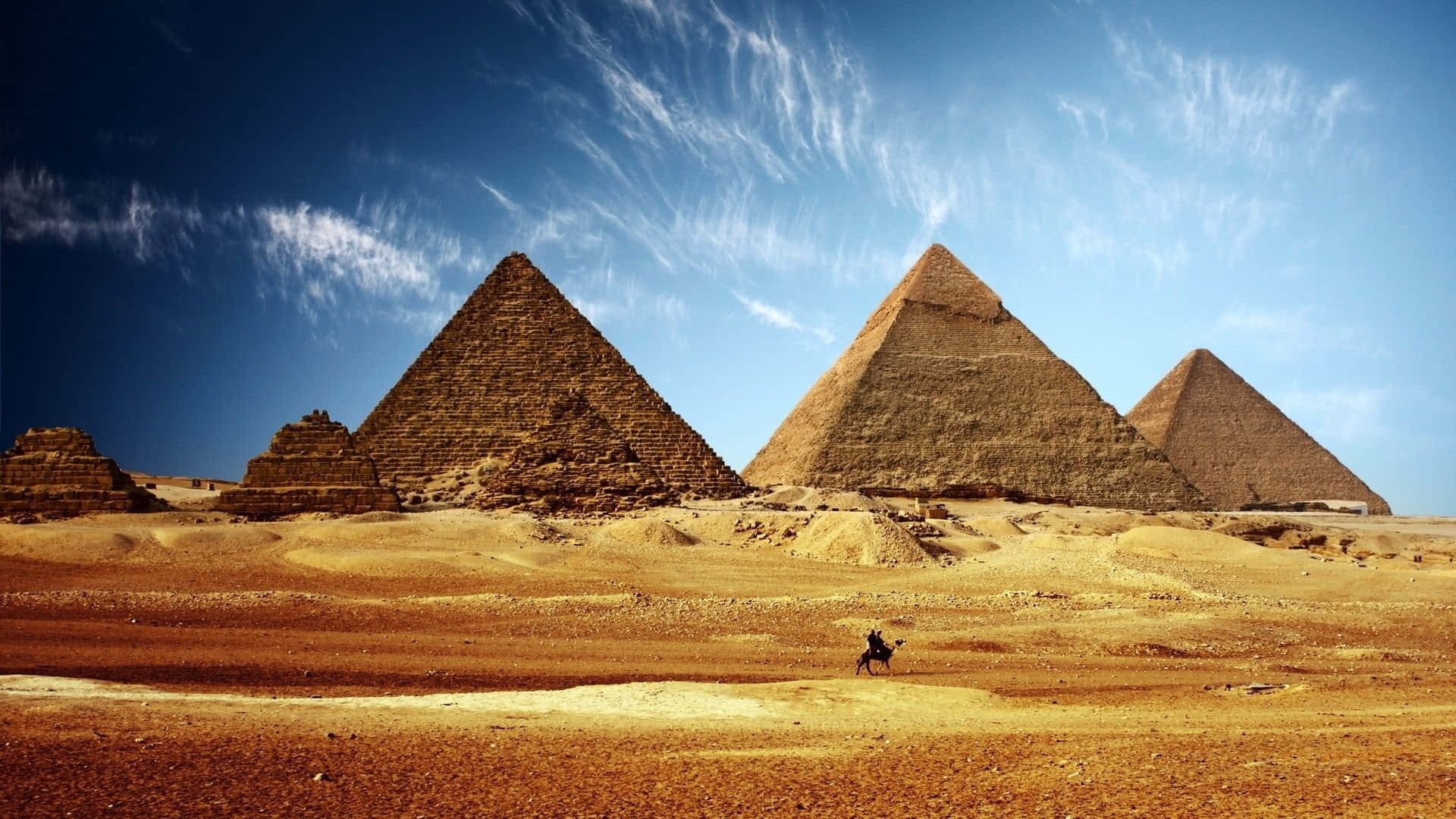 Egypt 桌布 壁紙 — 三座巨大的金字塔從金色沙漠中升起，在帶有縷縷薄雲的鮮豔藍天下。