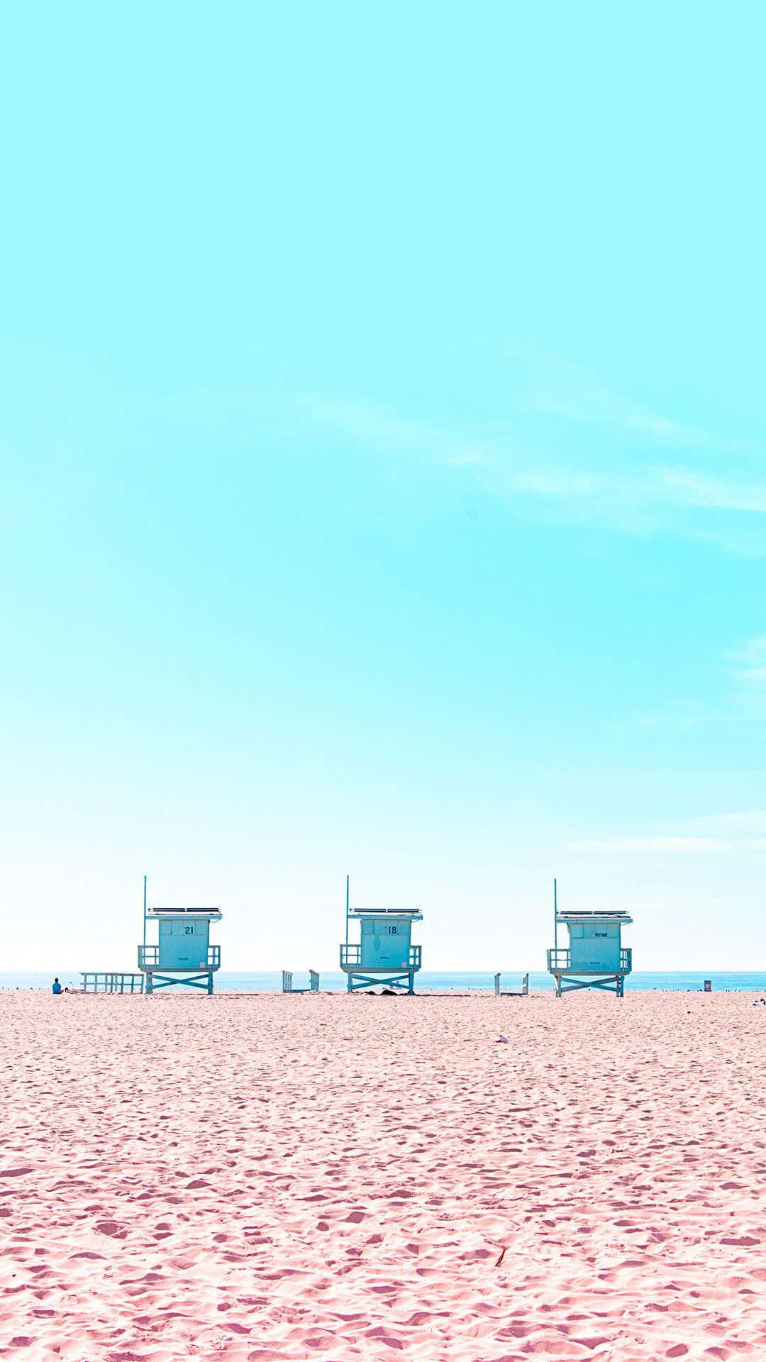 Minimalist Beach 桌布 壁紙 — 三座藍綠色的救生塔並排矗立在粉紅色沙灘上，上方是廣闊清澈的藍天。