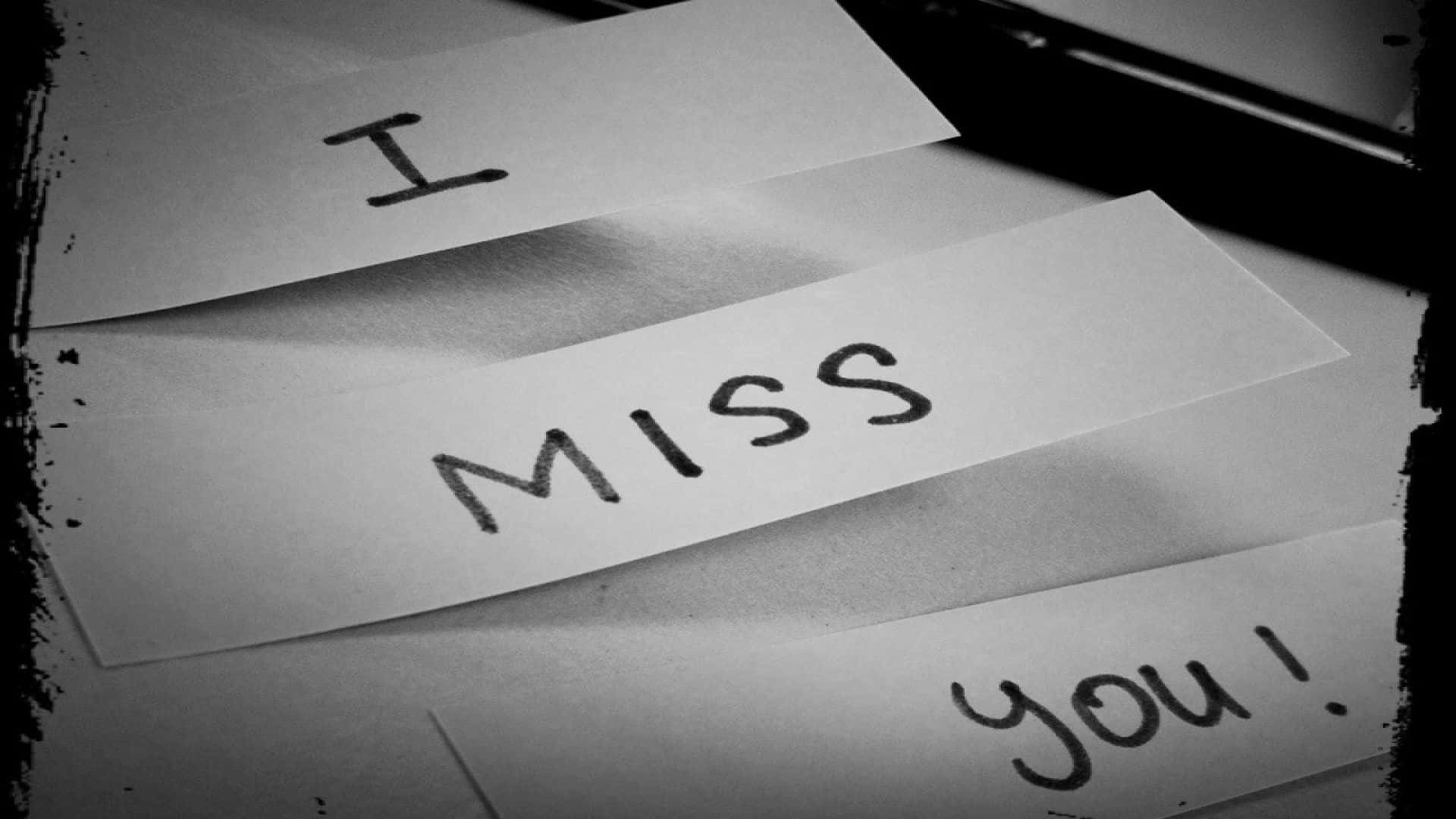 I Miss You 桌布 壁紙 — 三張手寫便條，用黑色墨水在紙上拼出「I Miss You!」，旁邊有一支筆，並以破舊邊框框住。