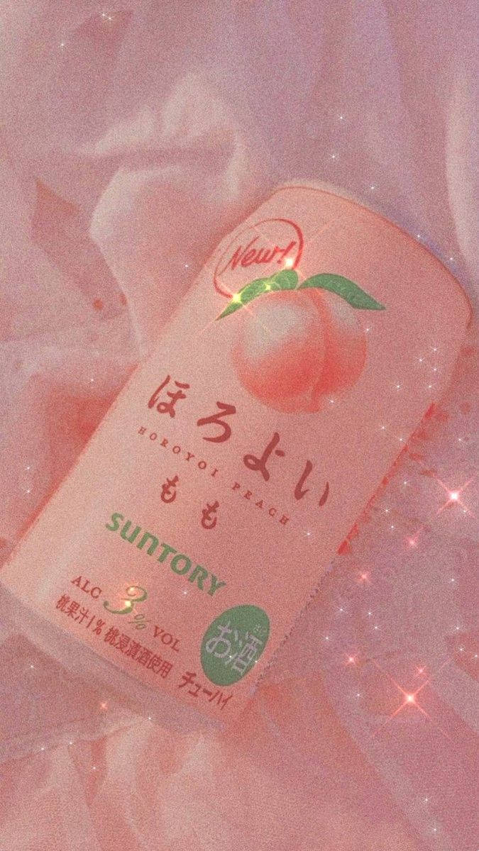 粉紅色Suntory桃味利口酒罐放在帶閃粉效果的粉紅色布料上。