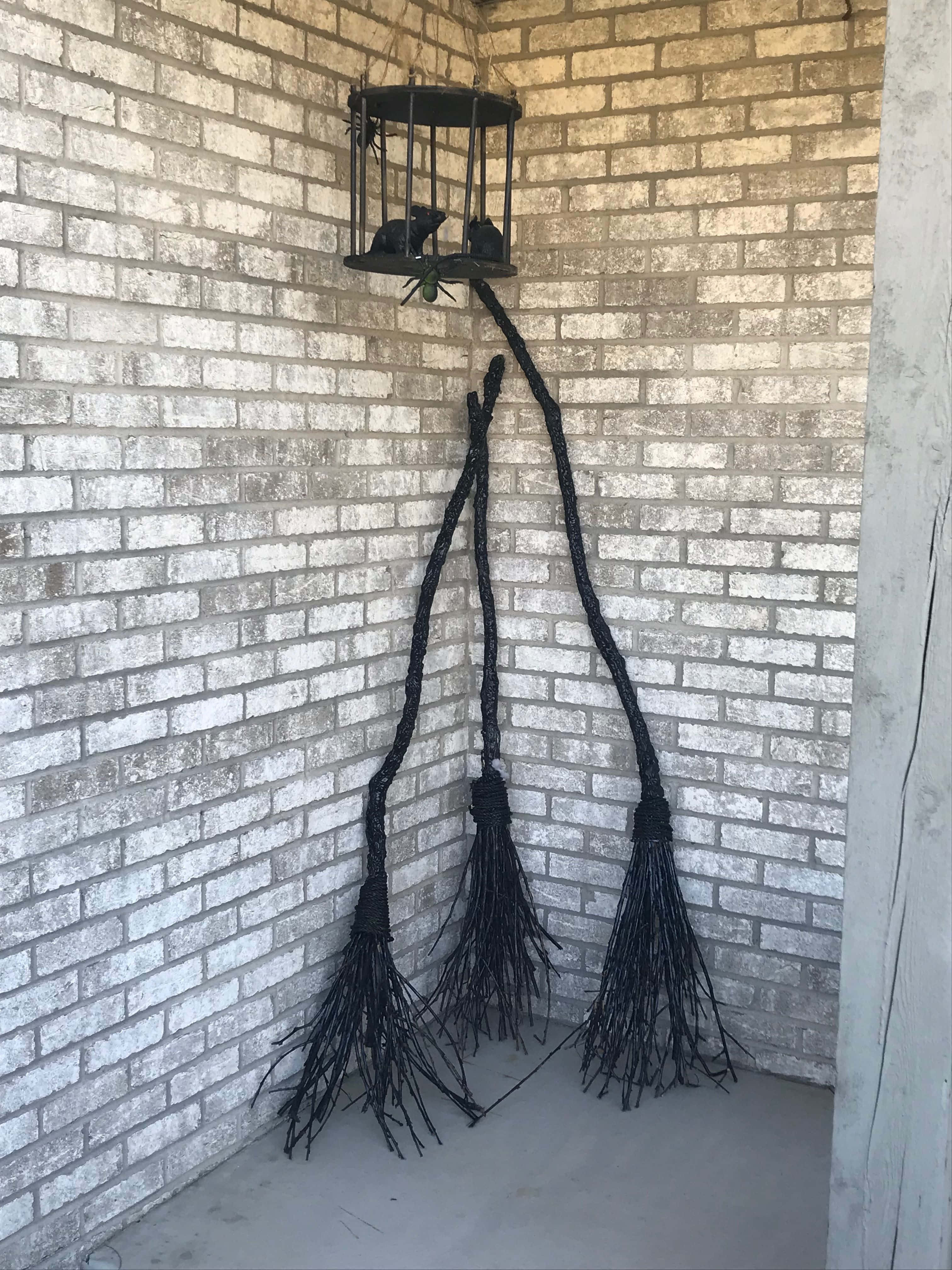 Witches Broom 桌布 壁紙 — 三把黑色女巫掃帚靠喺一個風化嘅磚牆上，下面掛住一個燈籠，上面有雀仔企喺度。