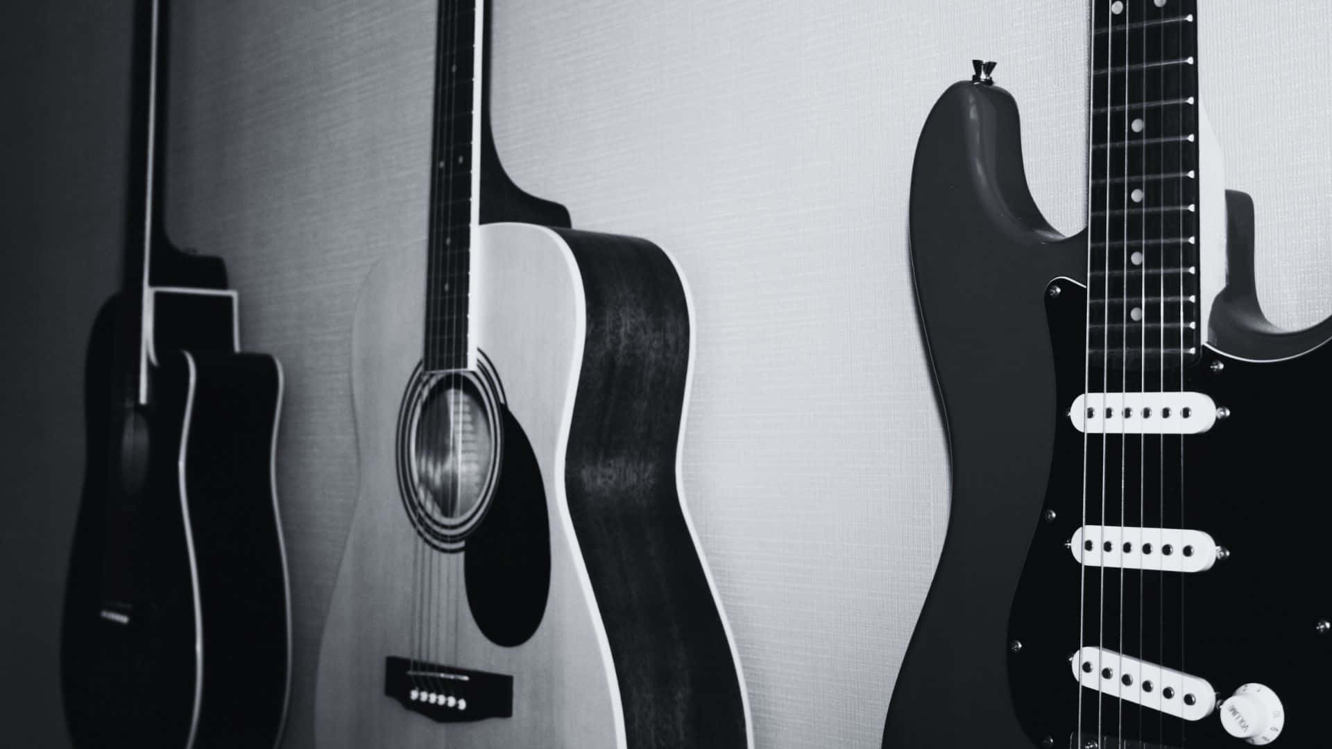 Black And White Guitar 桌布 壁紙 — 三支結他，包括木結他和電結他，以單色調靠在一面有紋理的牆上。