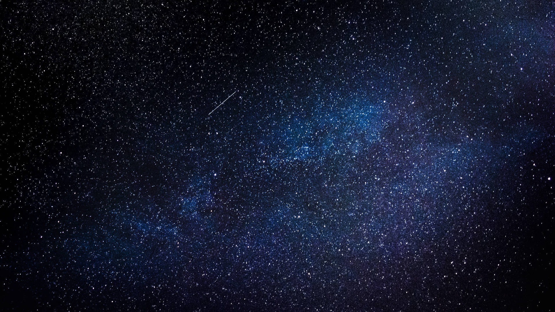 銀河系在深藍色中閃耀，繁星點點，一顆流星劃過夜空。