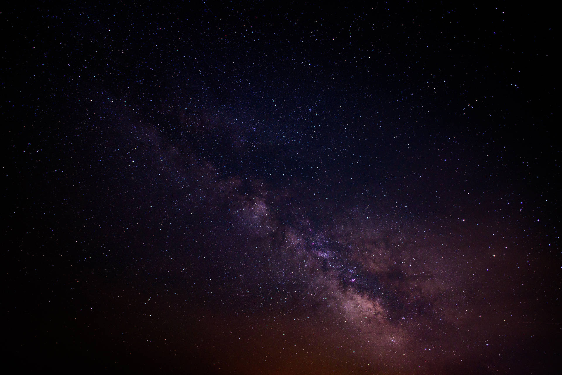銀河系在黑暗的夜空中閃爍著紫色和粉紅色的星星。