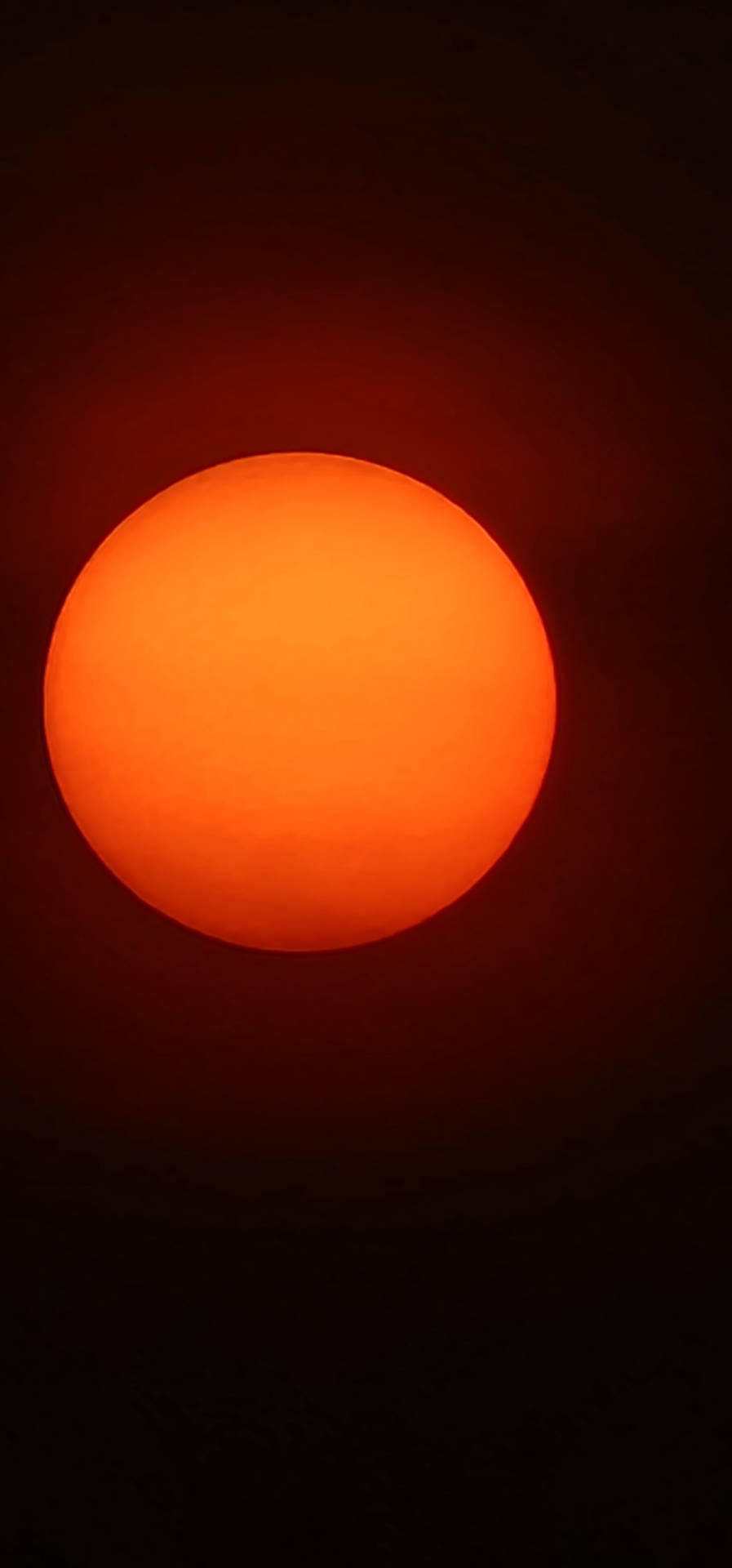 一顆明亮的橙色太陽在黑暗的天空中發光。 — 三星 Galaxy S22 壁紙