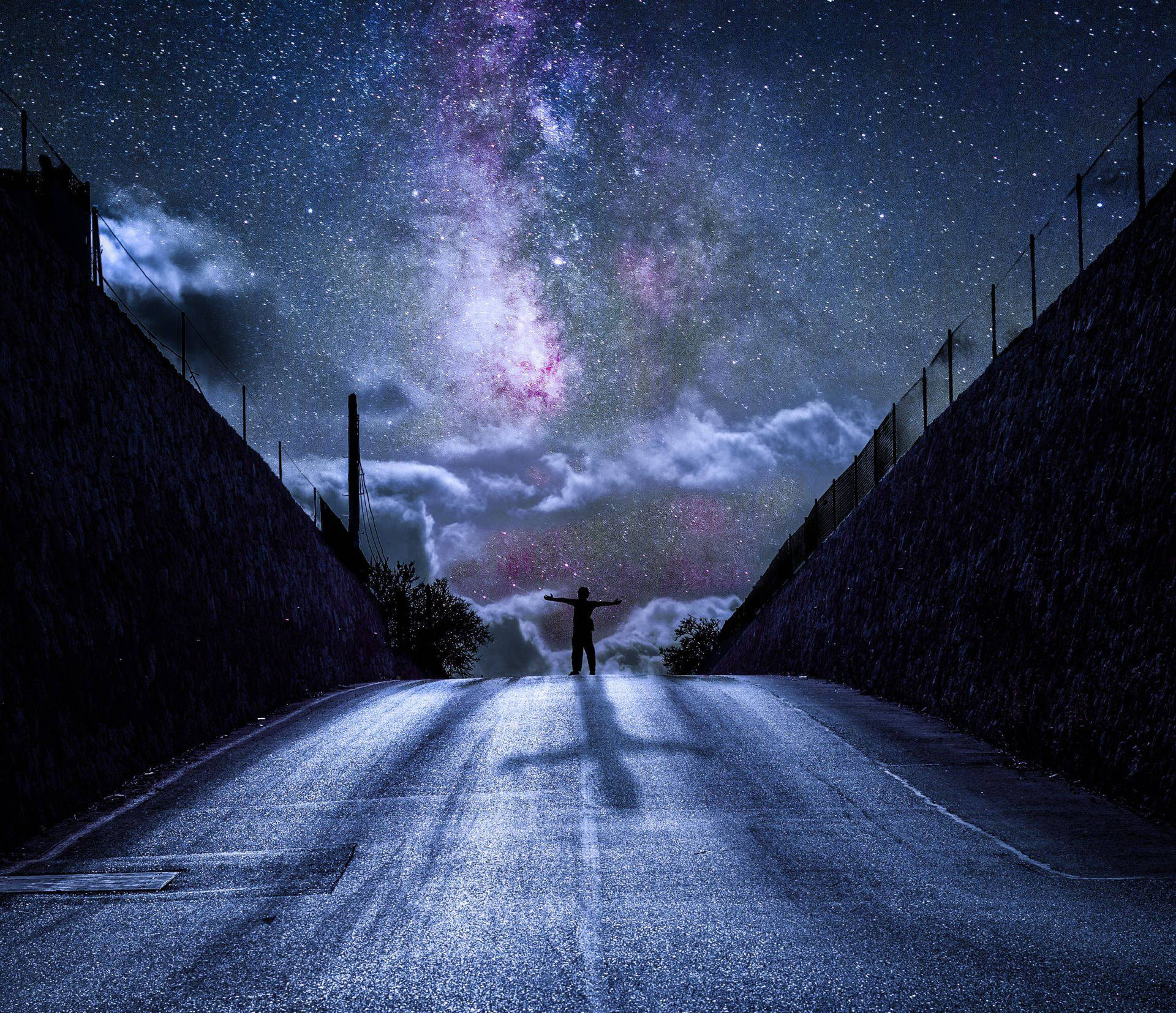 人在路上張開雙臂站在銀河夜空下