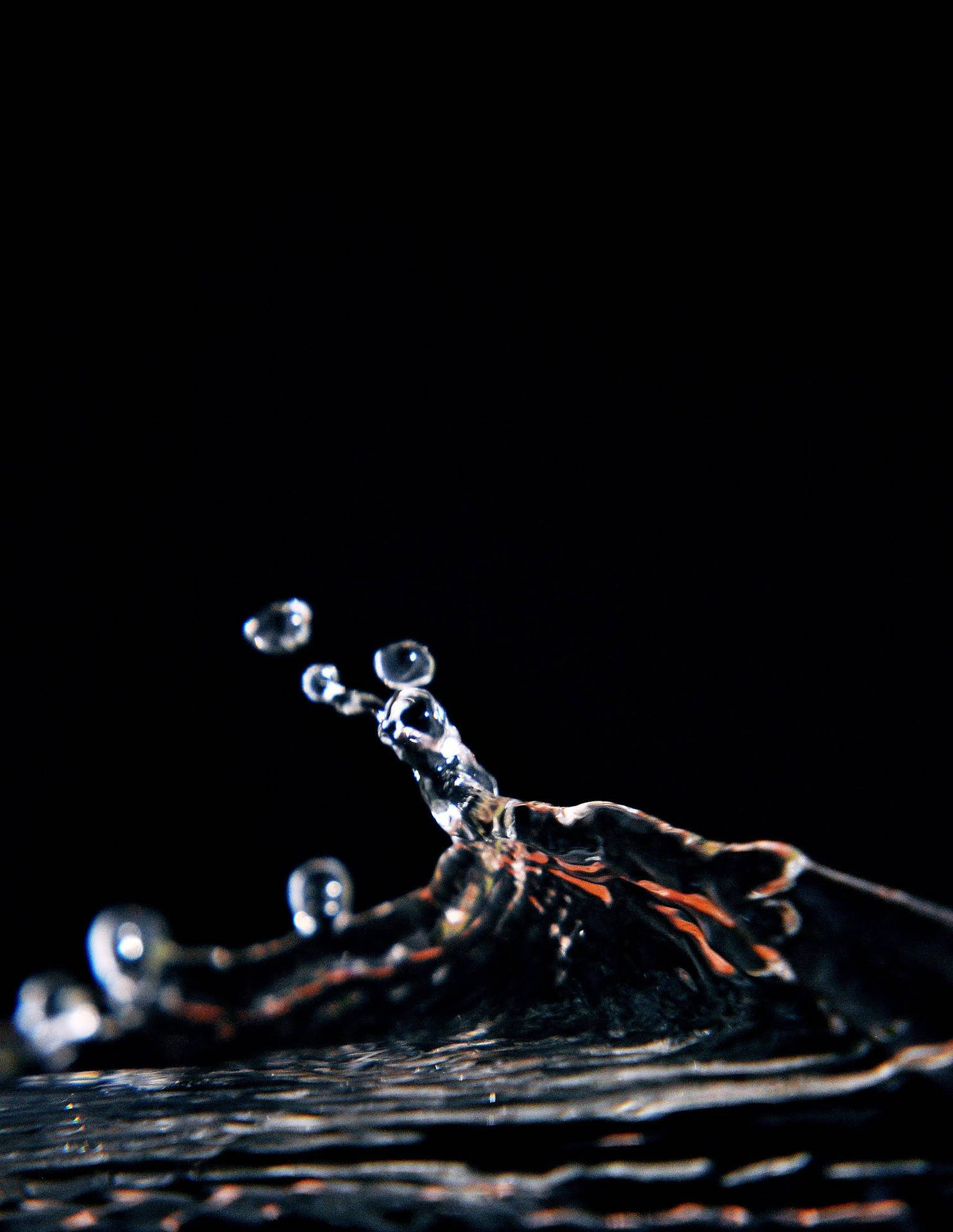 水滴飛濺中的特寫，背景為黑色，帶有橙色高光。