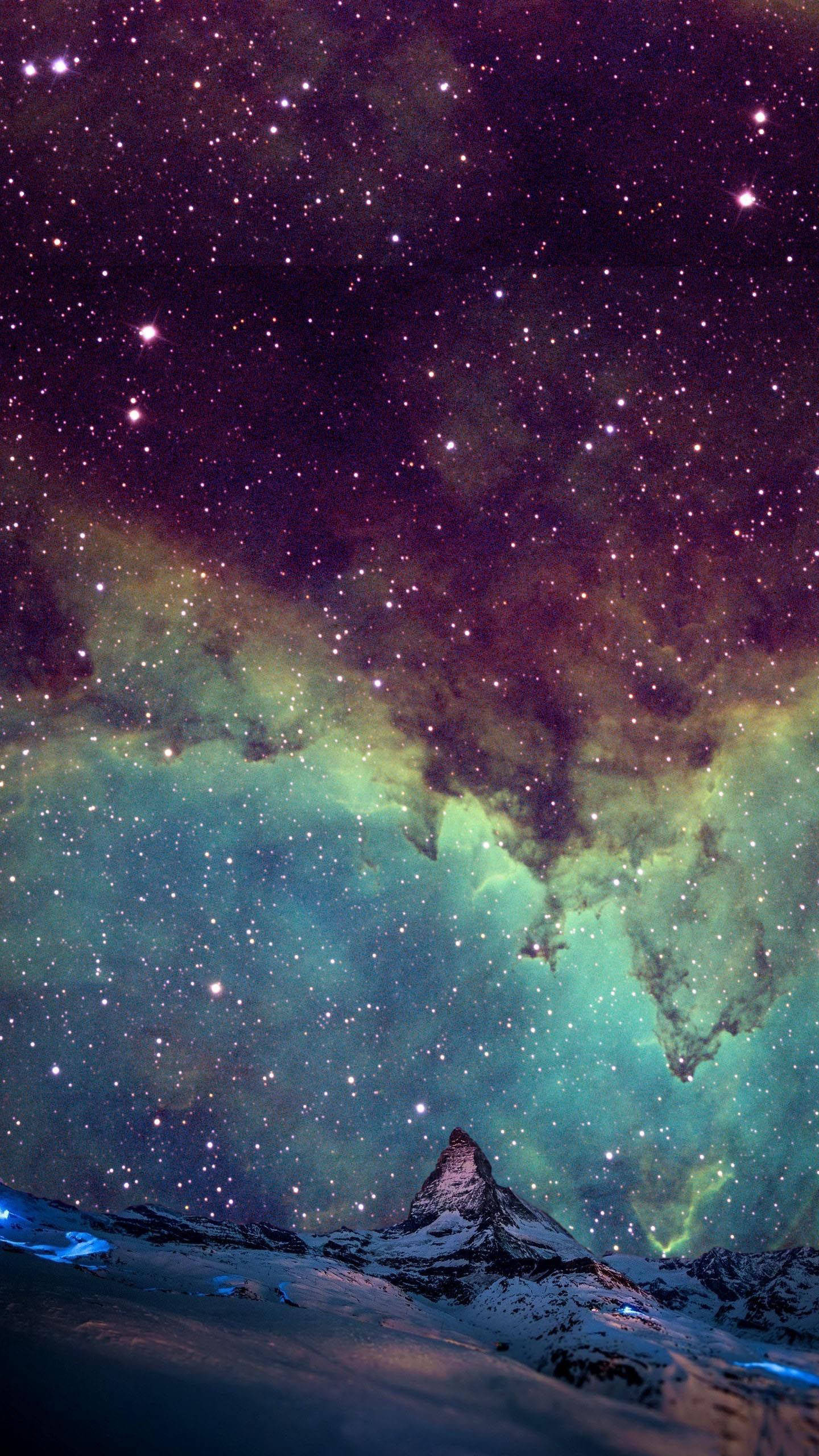 三星手機 星系天空 壁紙 — 白雪覆蓋的山峰在充滿星星和發光綠色星雲的充滿活力的宇宙天空下升起。