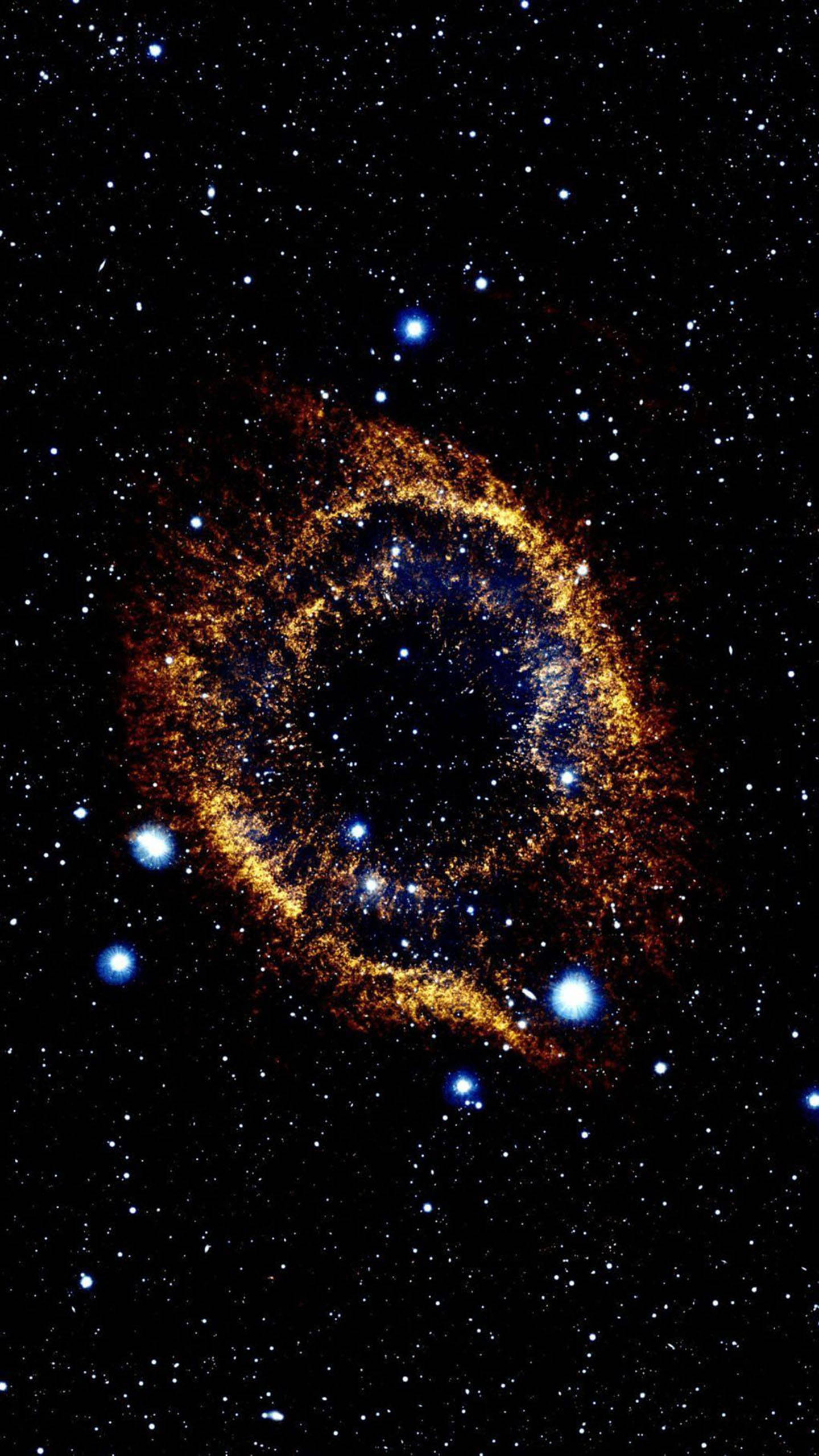 三星手機 螺旋星雲 壁紙 — 一個發光的金色環狀星雲在星場中旋轉，明亮的藍色星星散落在黑色虛空中。