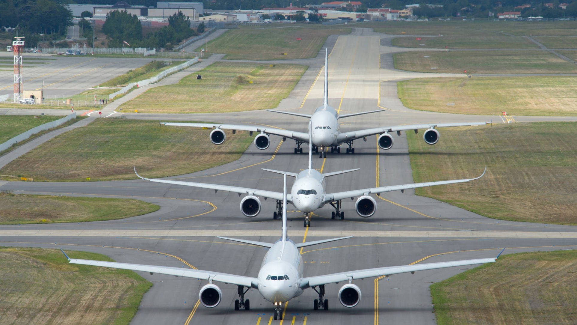 三架A380準備起飛 壁紙 — 三架大型白色客機在晴朗日光下排列在機場跑道上，周圍有草地和遠處建築物。