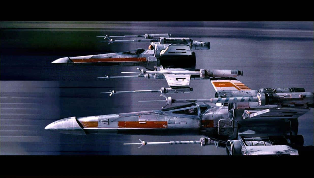 X-wing Fighter 桌布 壁紙 — 三架X翼星際戰鬥機在黑暗的宇宙背景下，帶着動態模糊效果劃過太空。