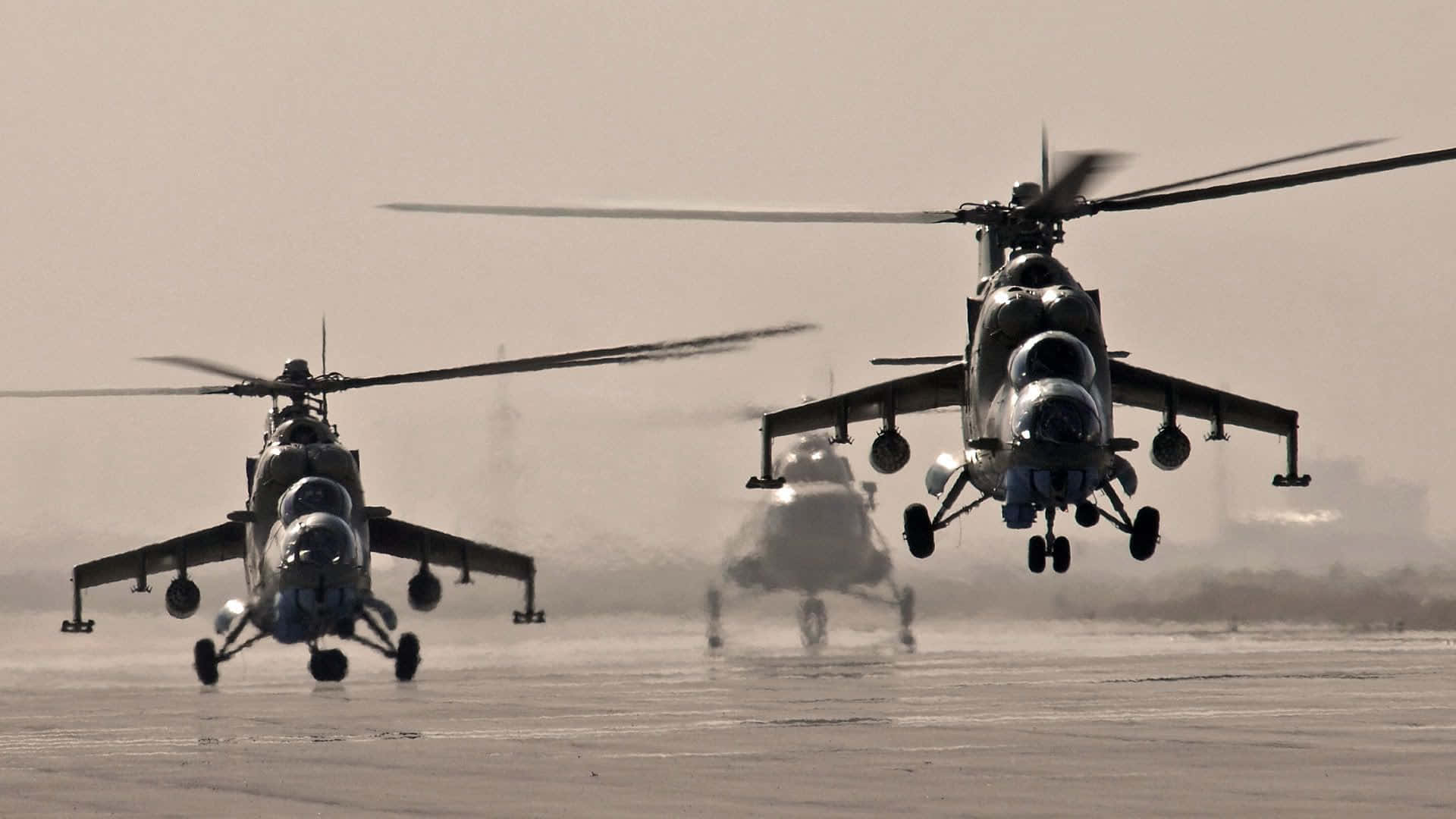 直升機 桌布 壁紙 — 三架軍用直升機低空盤旋在塵土飛揚的機場上，揚起沙塵，準備起飛。
