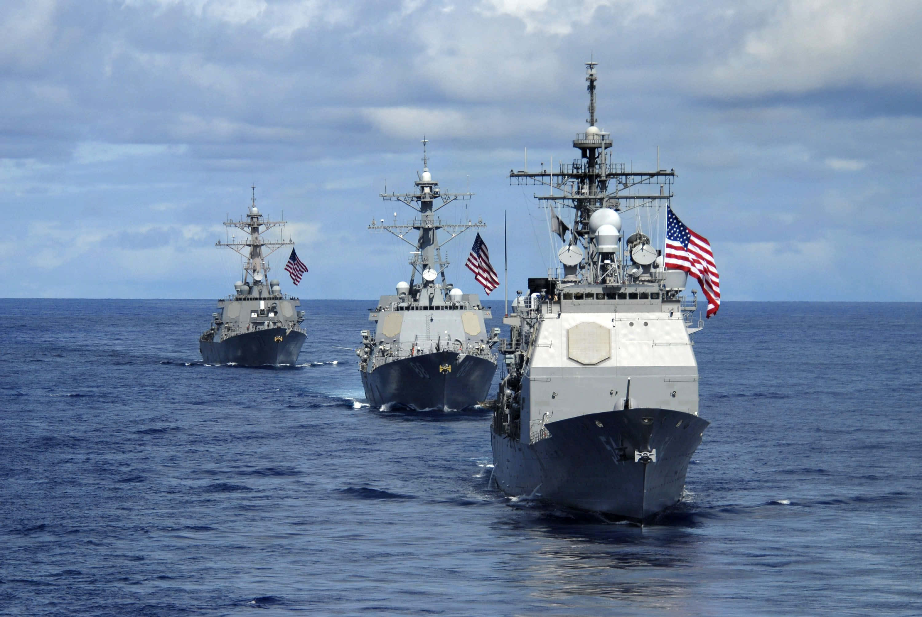 Navy 桌布 壁紙 — 三艘灰色嘅美國海軍軍艦喺多雲嘅天空下，以編隊形式航行喺廣闊嘅藍色海洋上。