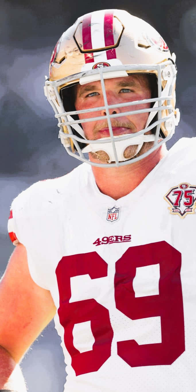 Mike Mcglinchey 桌布 壁紙 — 三藩市四九人美式足球員身穿頭盔及69號球衣，在模糊的球場背景下拍攝的特寫肖像。