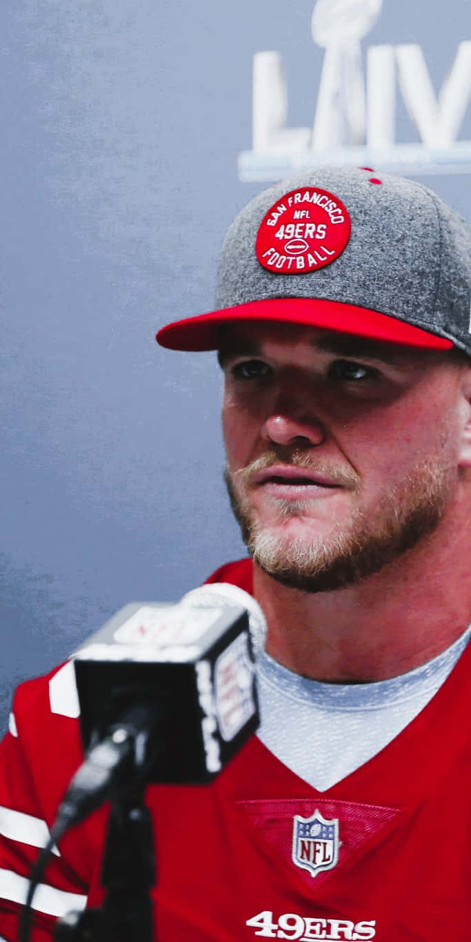 Mike Mcglinchey 桌布 壁紙 — 三藩市四九人美式足球員近照，身穿球隊帽和球衣，在記者會上使用麥克風。