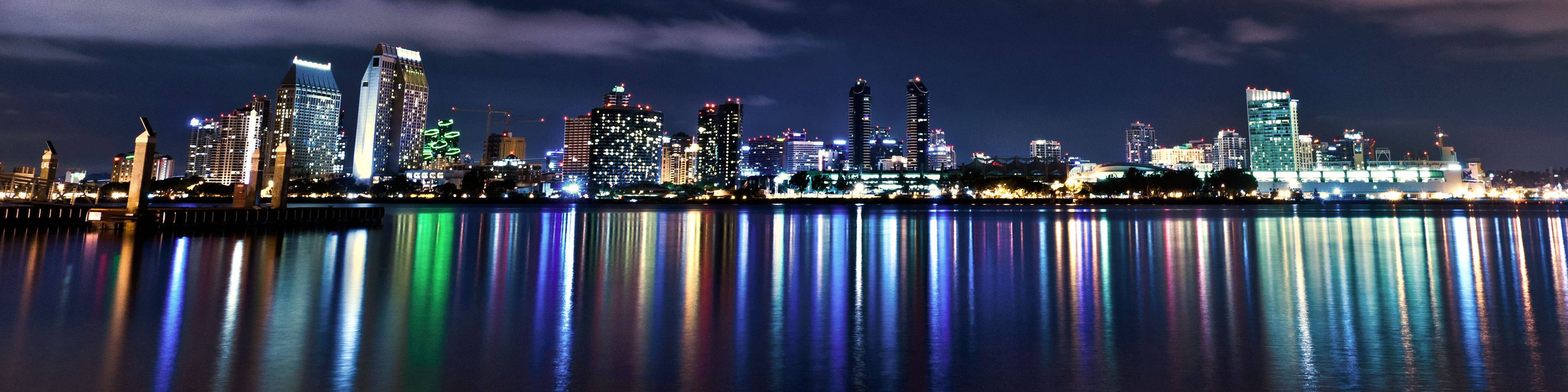 夜晚的城市天際線，色彩繽紛的燈光倒映在平靜的水面上。
