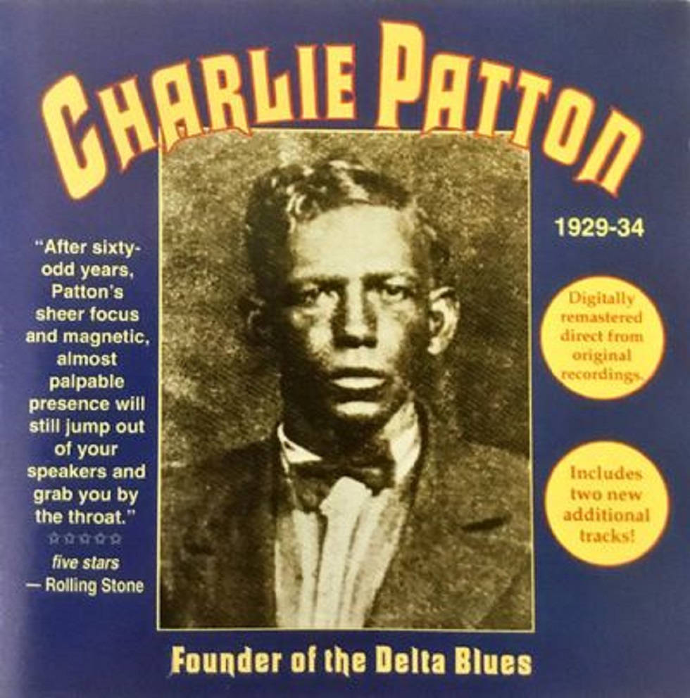 三角洲藍調先驅查理·帕頓的震撼肖像 壁紙 — 查理·帕頓（Charlie Patton）的復古棕褐色肖像，他是三角洲藍調的創始人，藍色專輯封面配有黃色文字和引言。