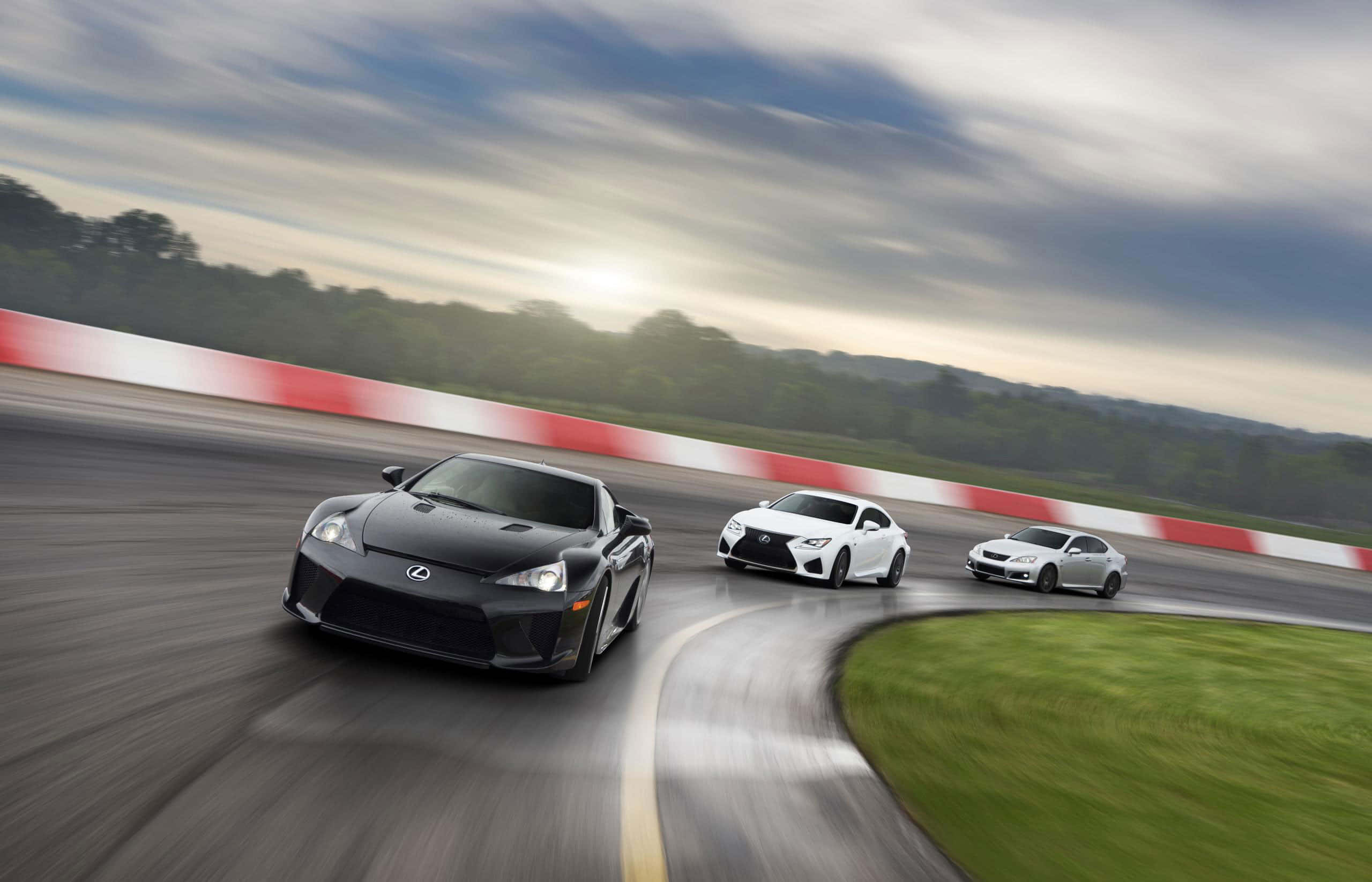 Lexus Lfa 桌布 壁紙 — 三輛時尚的 Lexus 跑車在蜿蜒的賽道上奔馳，呈現模糊動感，頭頂是陰天。