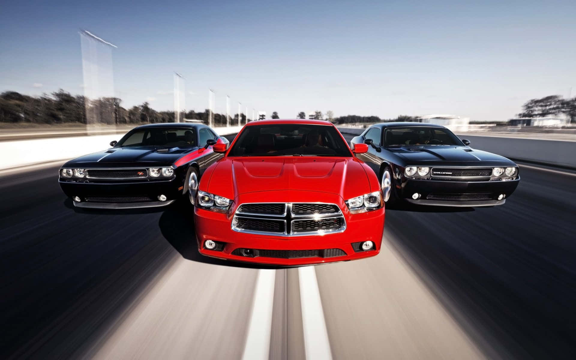 Dodge Charger 桌布 壁紙 — 三輛紅色和黑色的道奇挑戰者在晴朗藍天下以動態模糊效果在賽道上競速。