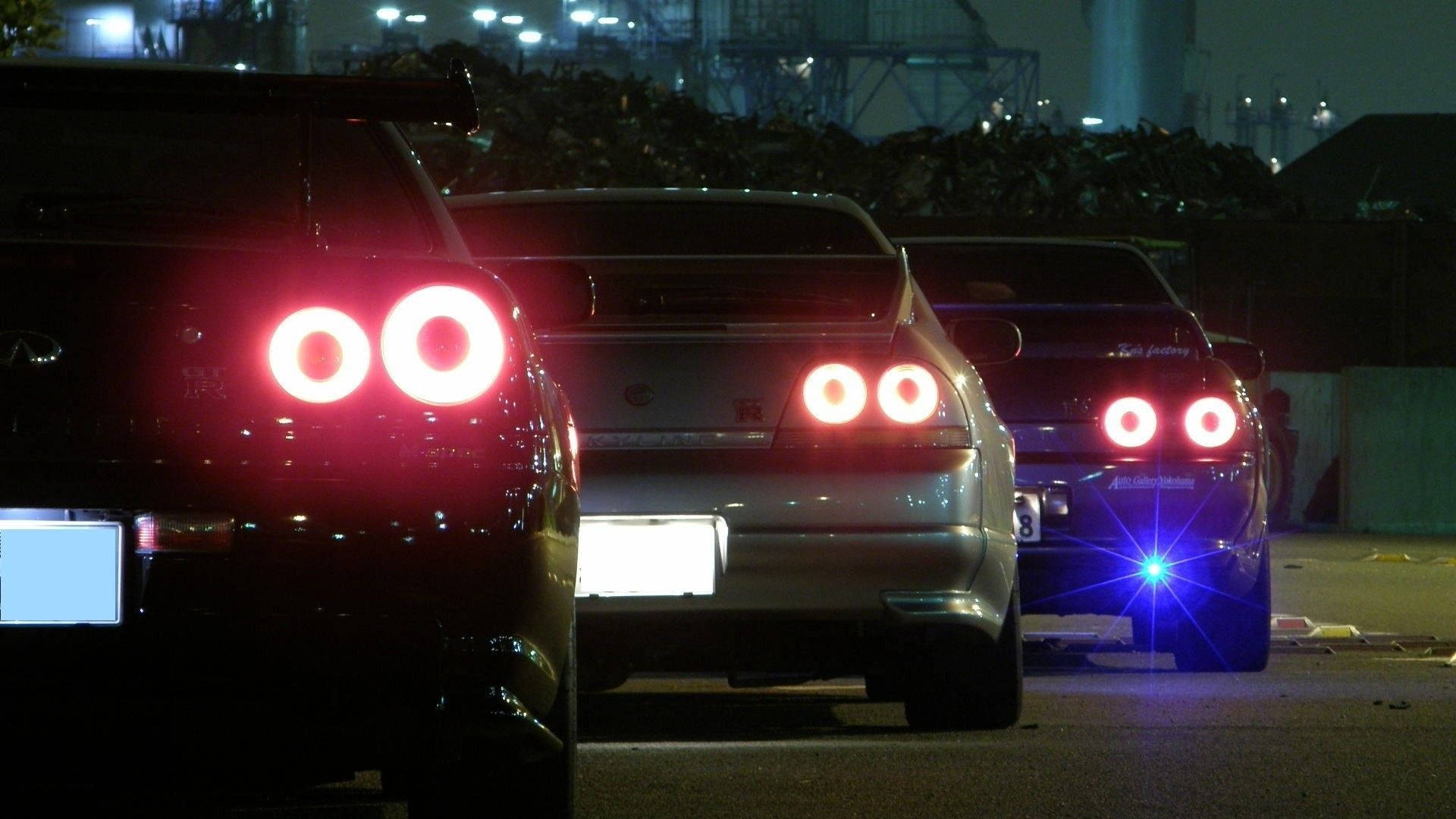 Jdm 美學 桌布 壁紙 — 三輛跑車在夜間於工業區排成一列，發出紅色圓形尾燈的光芒。