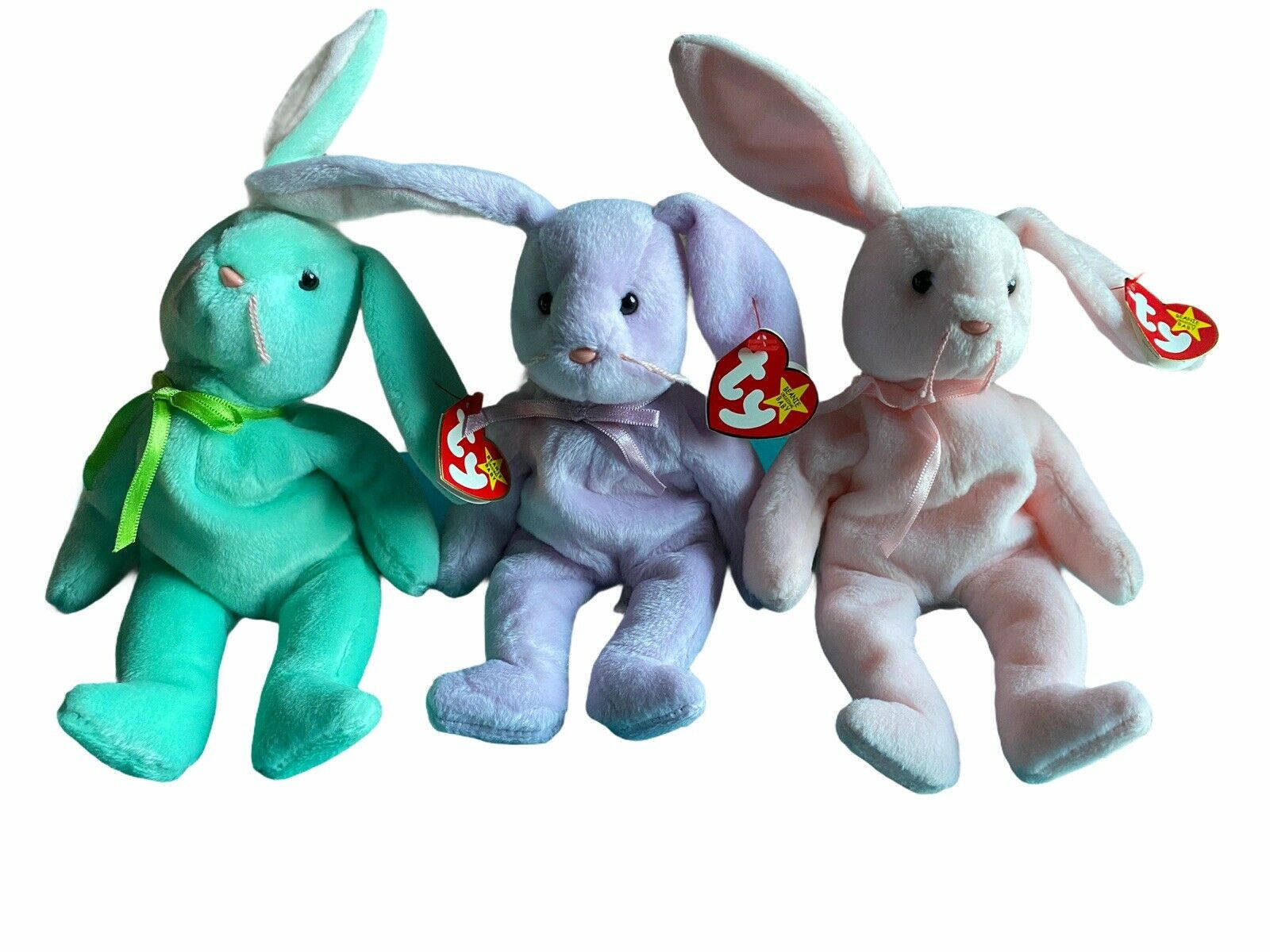 三隻兔兔Beanie Boos 壁紙 — 三隻 Ty Beanie Babies 兔子，顏色分別為青綠色、薰衣草色和粉紅色，並排坐在純白色背景前。