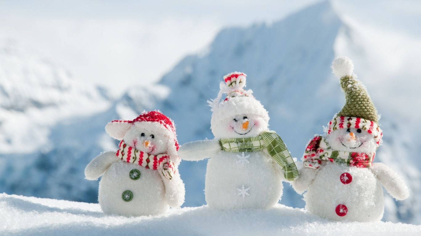 三個雪人戴著帽子和圍巾站在雪山上。 — 雪人 壁紙