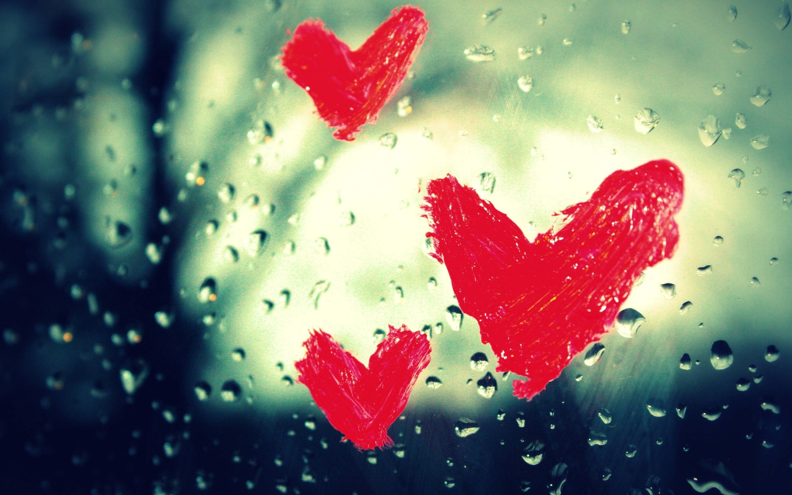 愛心 桌布 壁紙 — 三顆大膽的紅色心形畫在帶有雨點的窗戶上，背景光線柔和模糊。