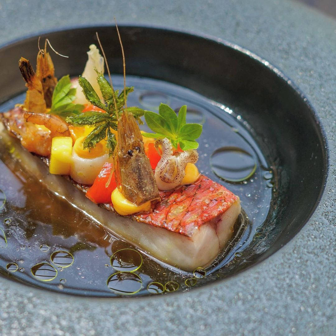 深色碗中的香煎魚柳、蝦仁及蔬菜配油滴