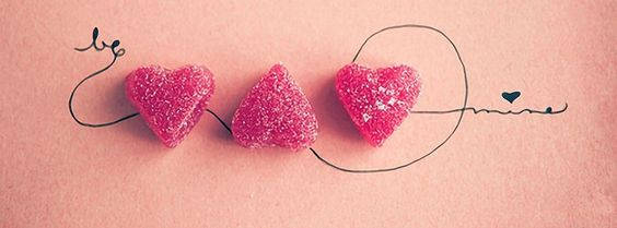 三顆粉紅色糖心糖果在粉紅色紙上拼出 be mine。