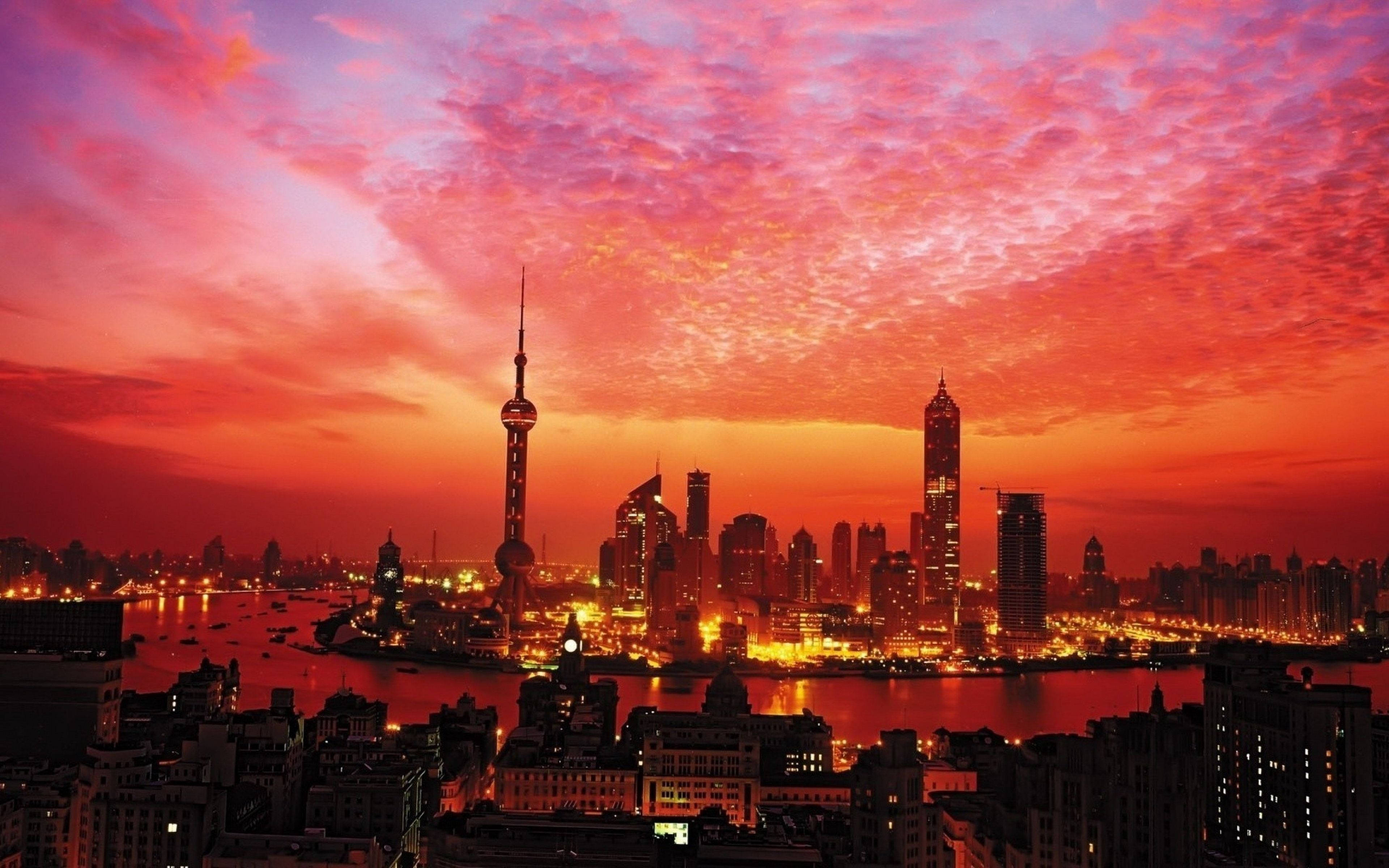 上海天際線日落 壁紙 — 夕陽將上海天際線染成火紅和橙色，城市燈光倒映在黃浦江上。