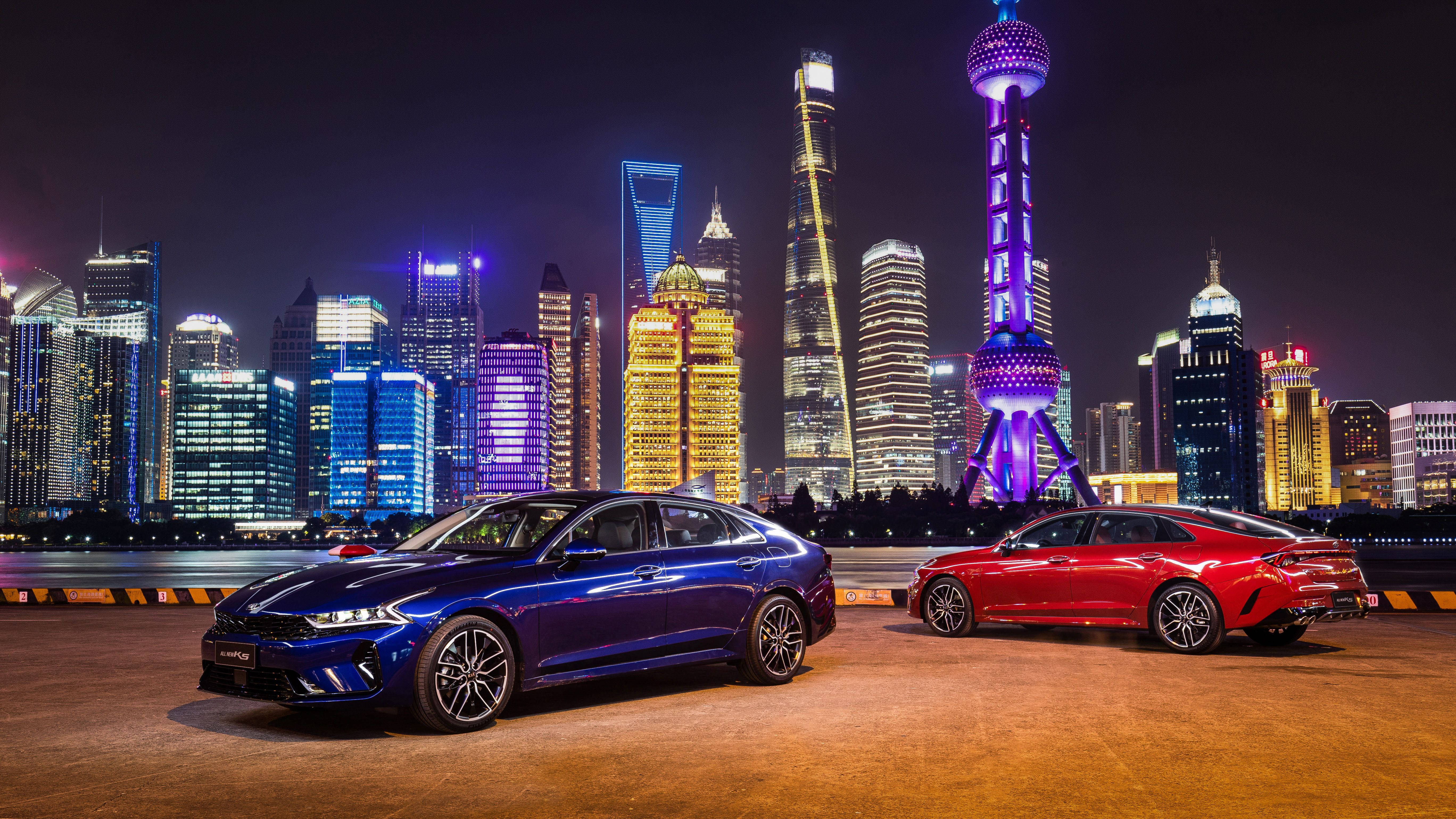 上海現代城市風景 壁紙 — 兩輛時尚轎車在夜晚的城市燈光下，映襯著上海標誌性的璀璨天際線。