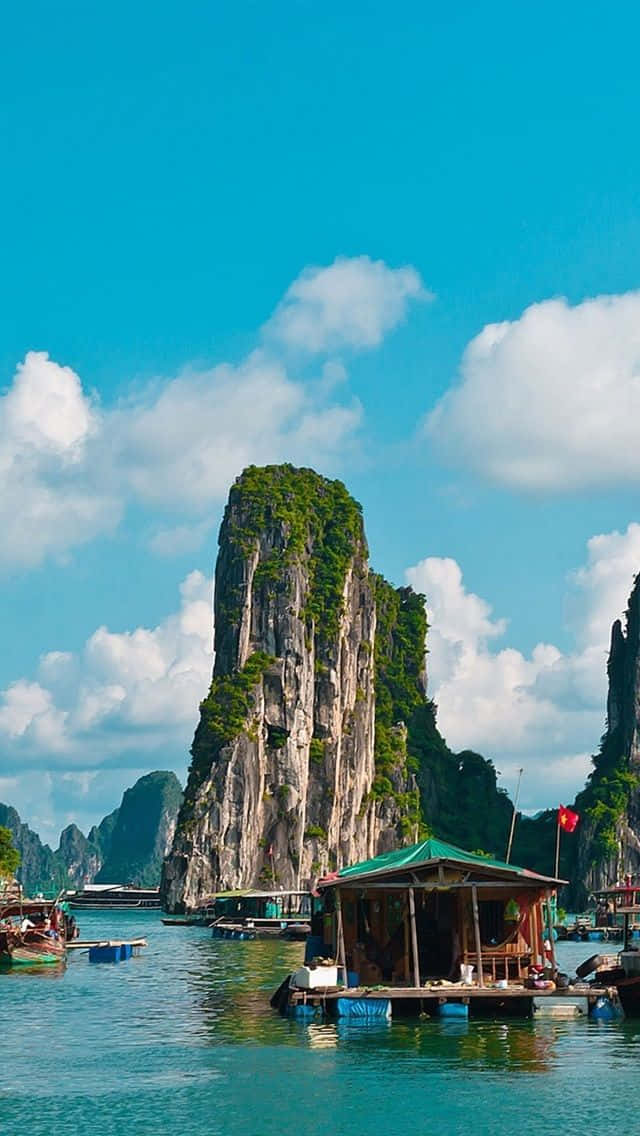 藍天下，石灰岩懸崖附近碧綠水面上漂浮的綠色屋頂木屋。