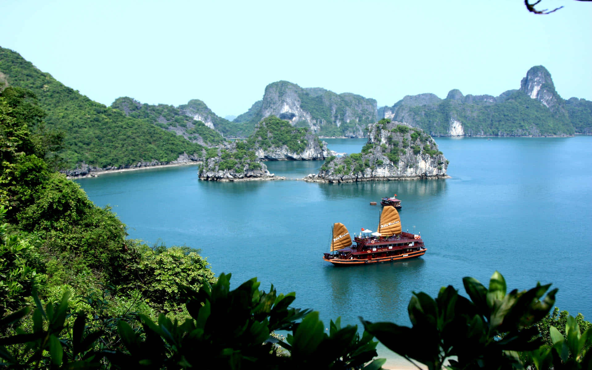 傳統帆船在碧綠海水中穿梭於綠色喀斯特島嶼之間。