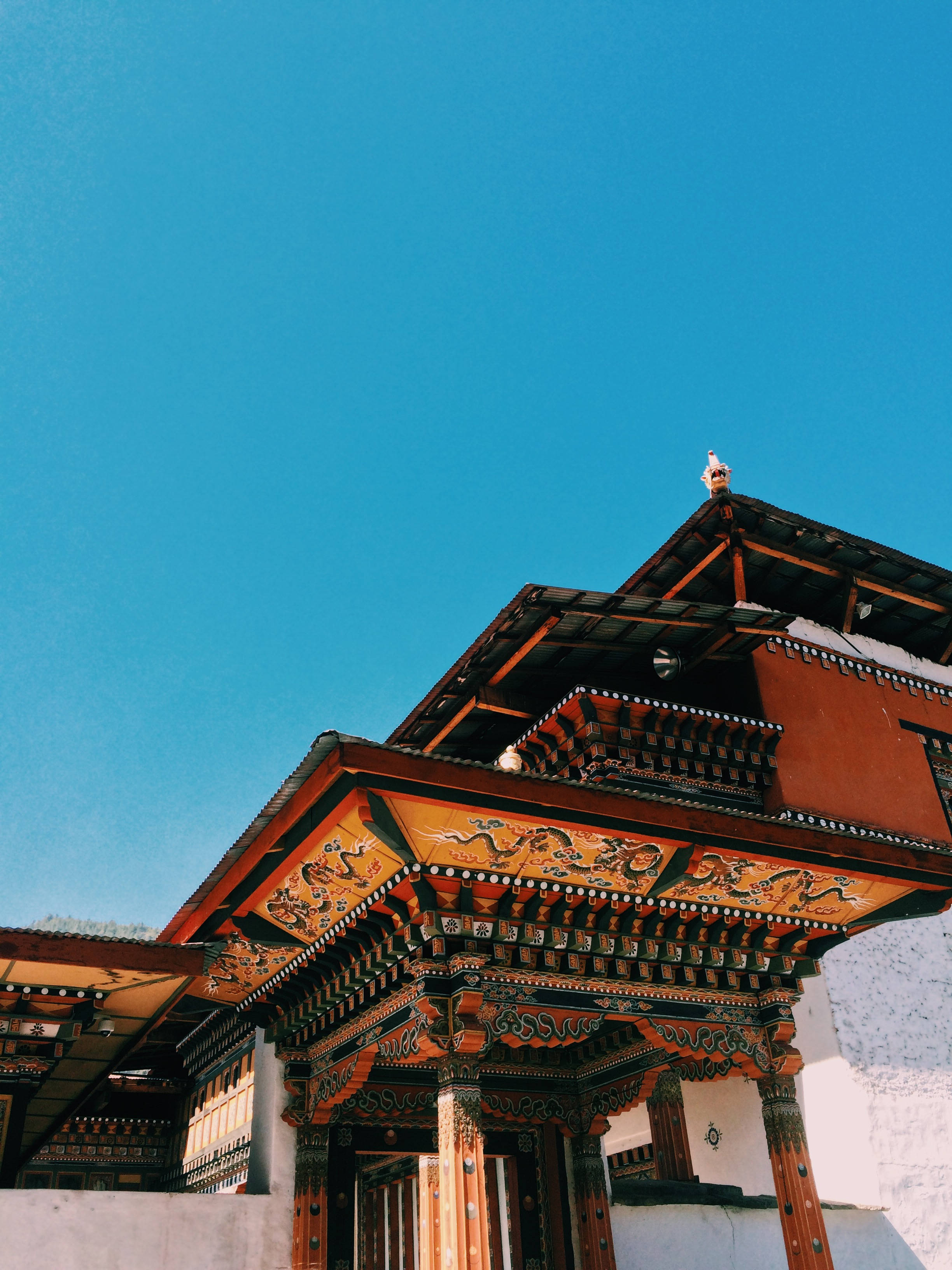 不丹彭措拉寺 壁紙 — 一座充滿活力的傳統不丹寺廟，擁有華麗的木雕和紅牆，矗立在清澈的藍天下。