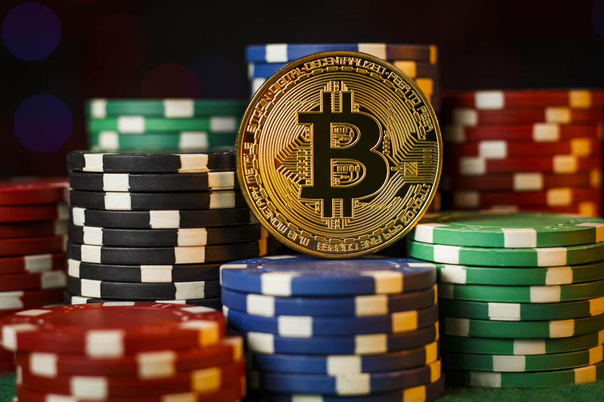 綠色氈面上的籌碼堆，頂部有一枚比特幣硬幣。 — 比特幣 壁紙
