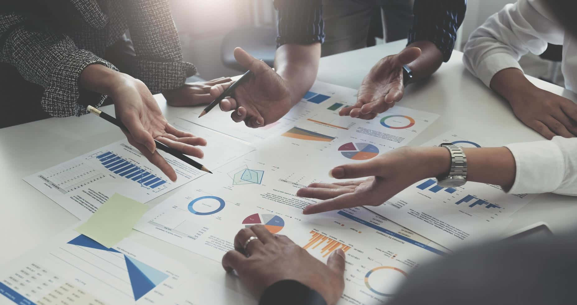 Teamwork 桌布 壁紙 — 不同專業人士的手在明亮的白色會議桌上協作分析色彩繽紛的圖表和圖形。