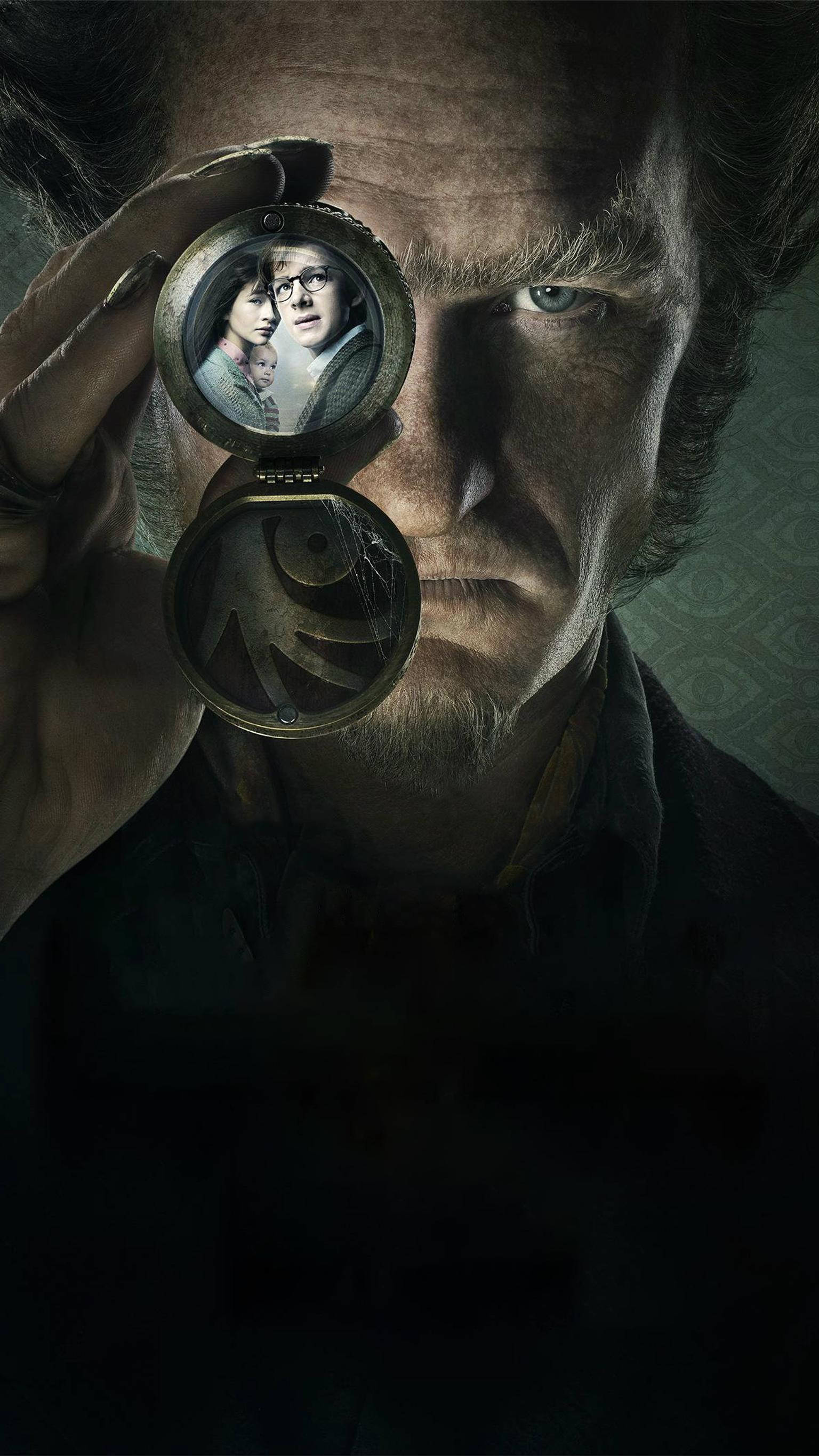 《不幸事件系列》Count Olaf 壁紙 — 一個眼神銳利的男人拿著一個小盒，裡面露出兩個孩子的照片，背景是深色紋理。