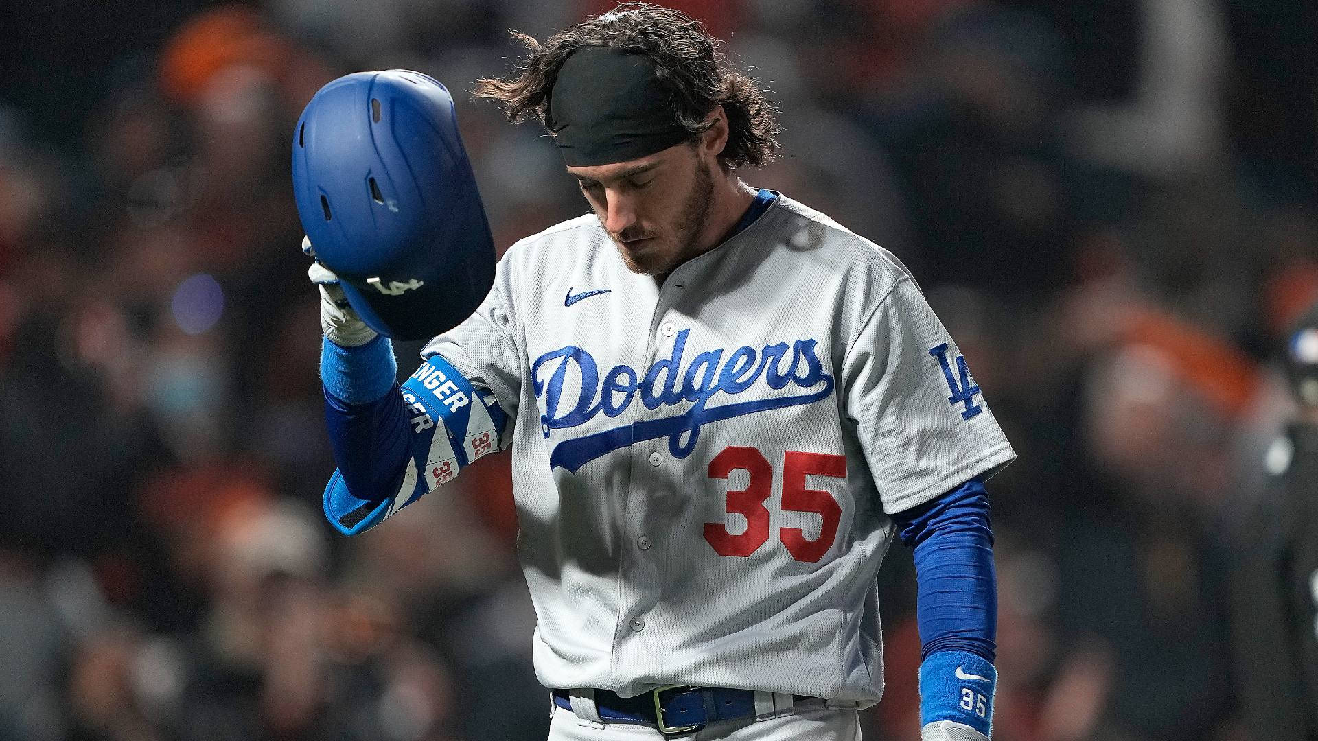 不悅的 Cody Bellinger 壁紙 — 一位身穿道奇隊35號球衣的棒球運動員在夜間球場低舉頭盔，低頭注視。
