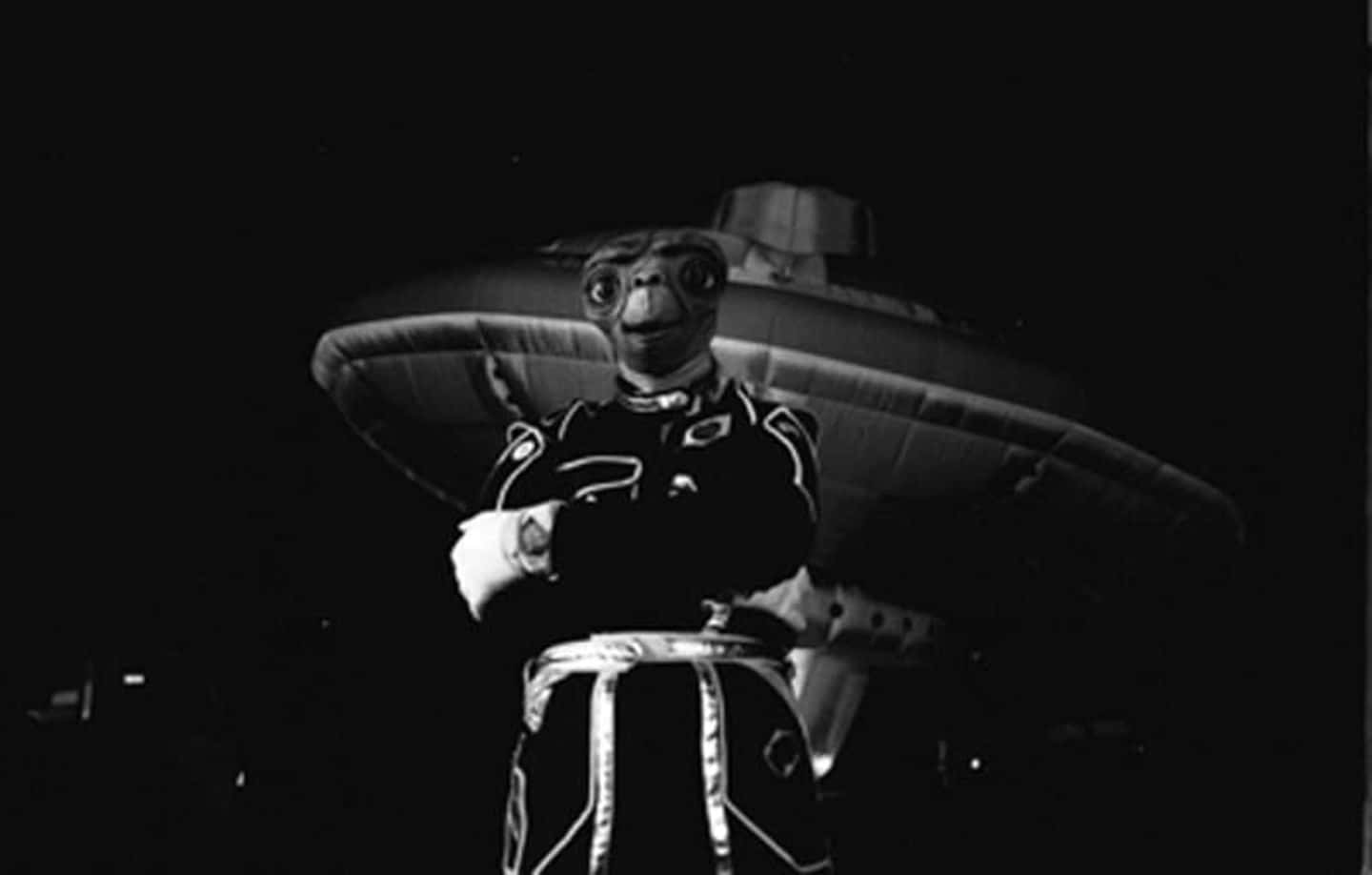 穿著戲服的外星人角色在夜晚站在飛碟前。