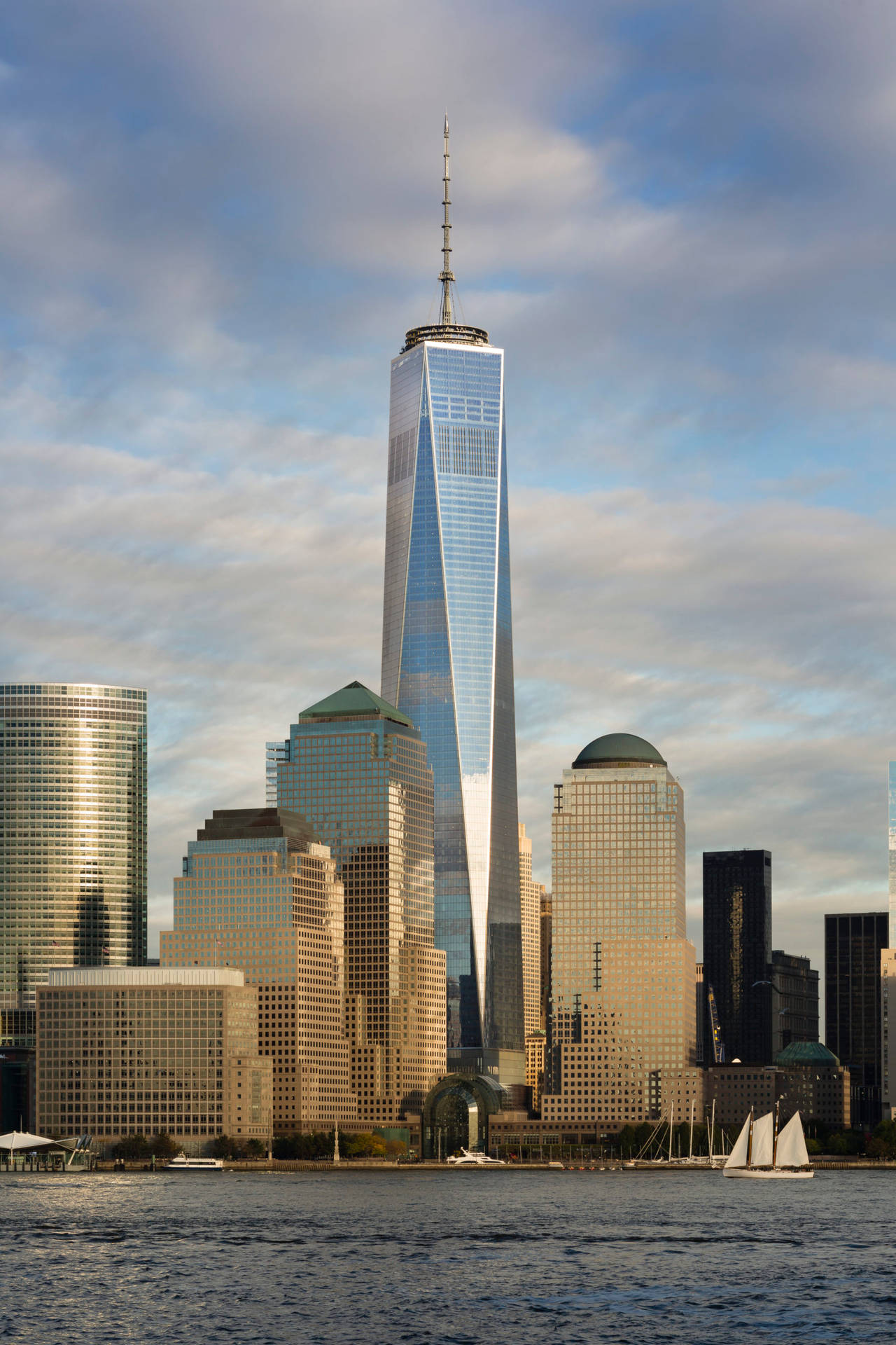 紐約市的One World Trade Center摩天大樓，在陰天下的水面上有帆船。
