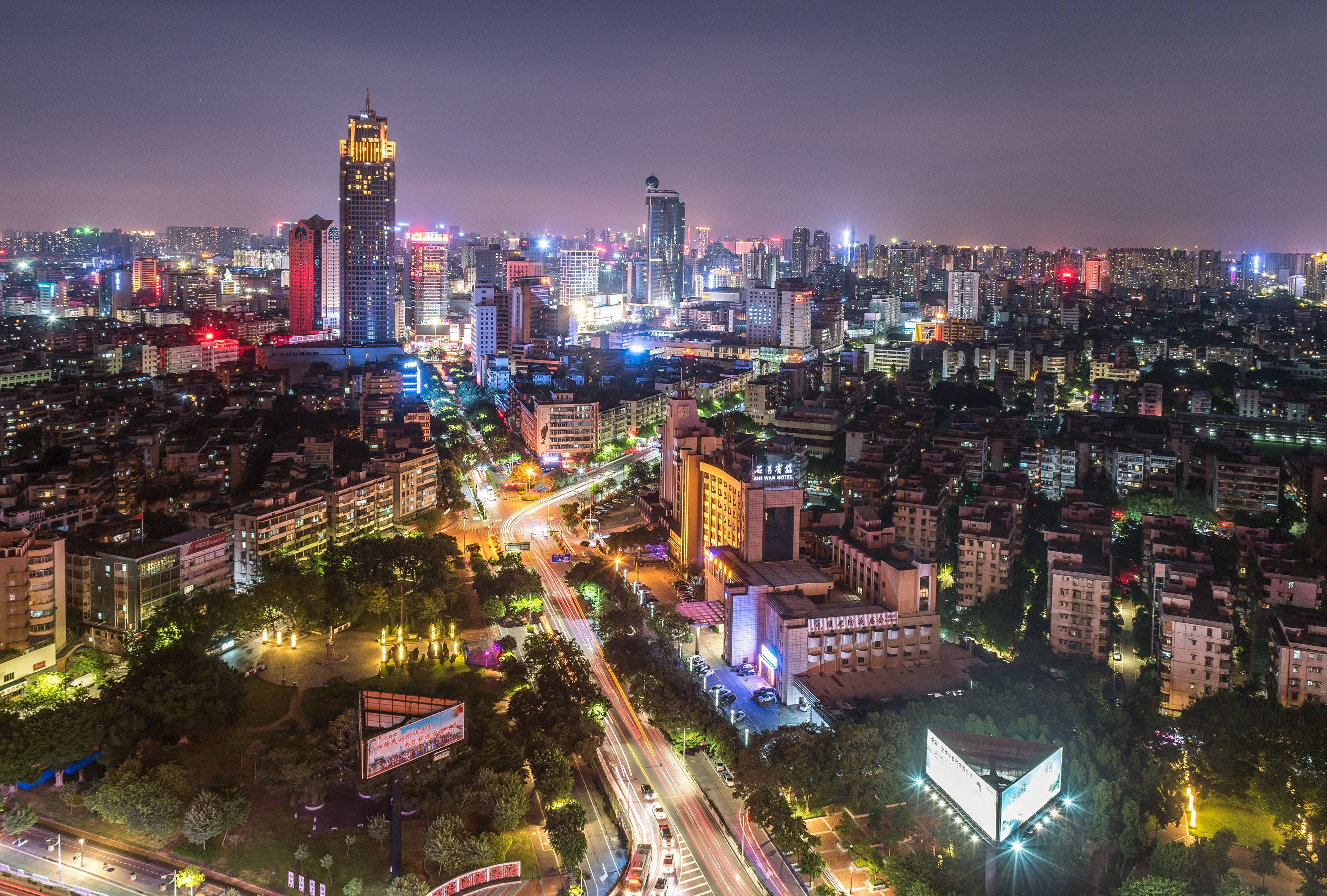 中國佛山城市 壁紙 — 繁忙城市景觀的夜間鳥瞰圖，閃爍的摩天大樓和穿梭於密集城市街區的車流光軌。