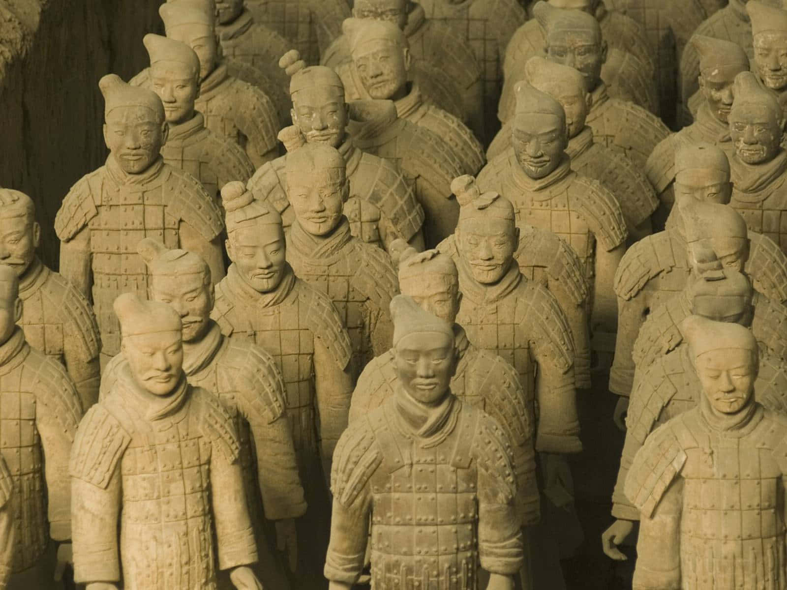 中國博物館內的兵馬俑石雕 壁紙 — 一排排古老的兵馬俑在溫暖的燈光下莊嚴列隊，展現出精細的盔甲和獨特的面部表情。