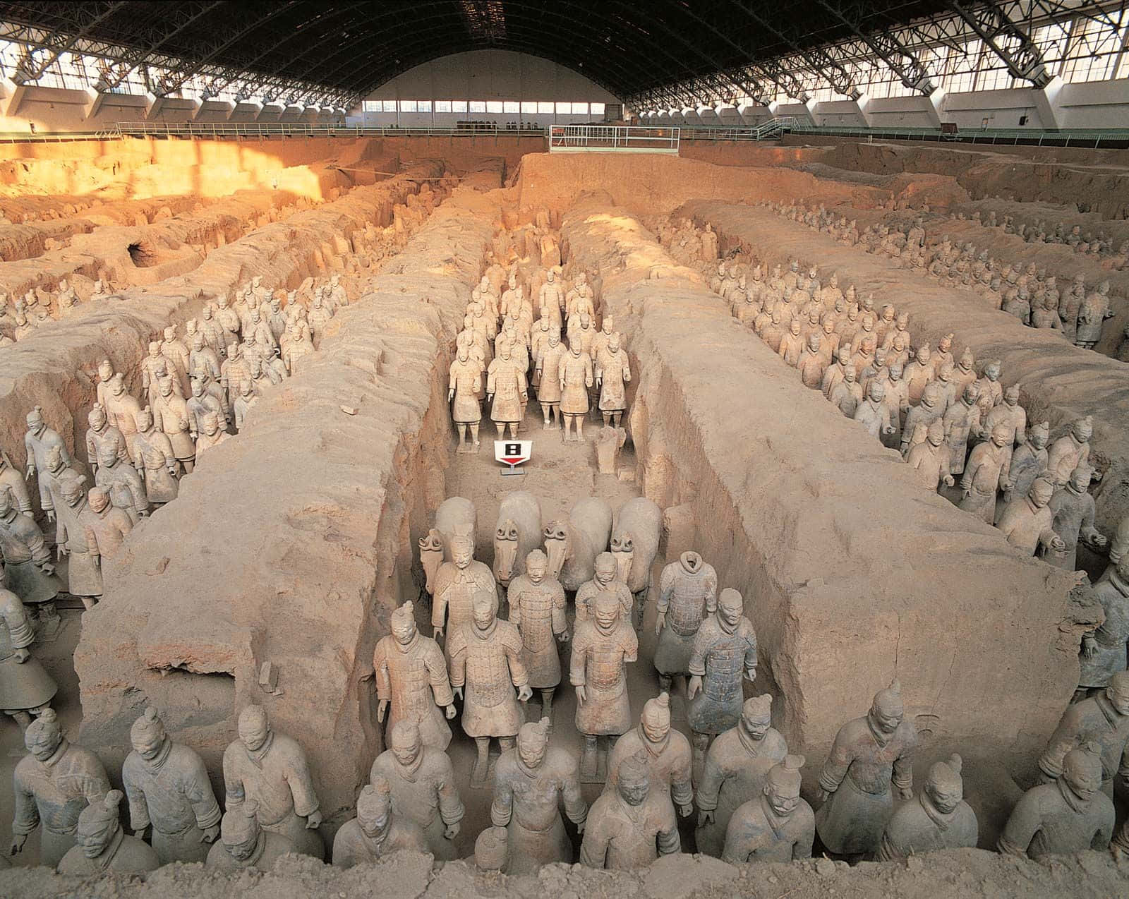中國博物館內的大型秦俑展覽 壁紙 — 一排排古代兵馬俑在巨大的地下發掘坑中整齊列陣。